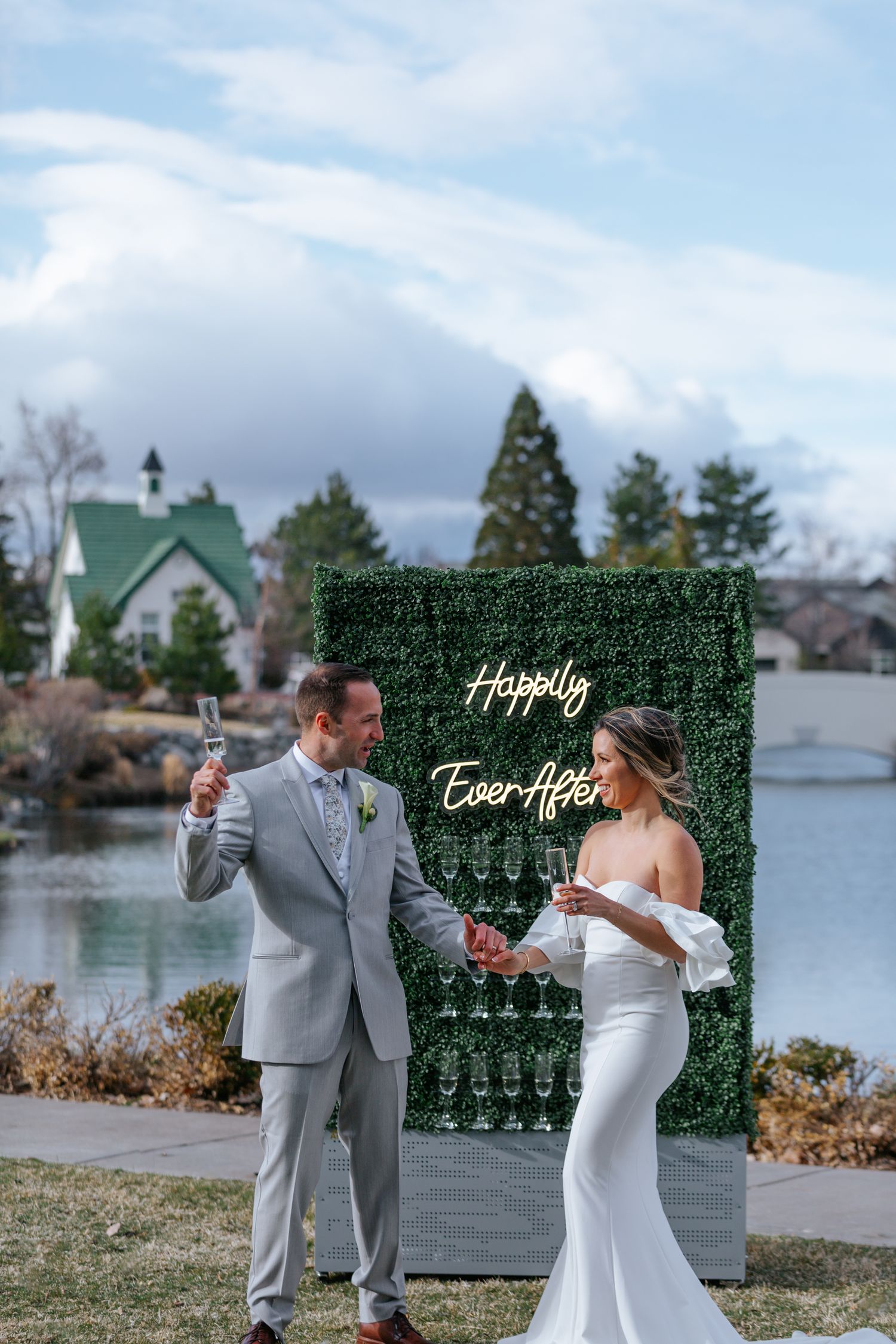 A decorative green wall backdrop with champagne glass display at an outdoor venue.