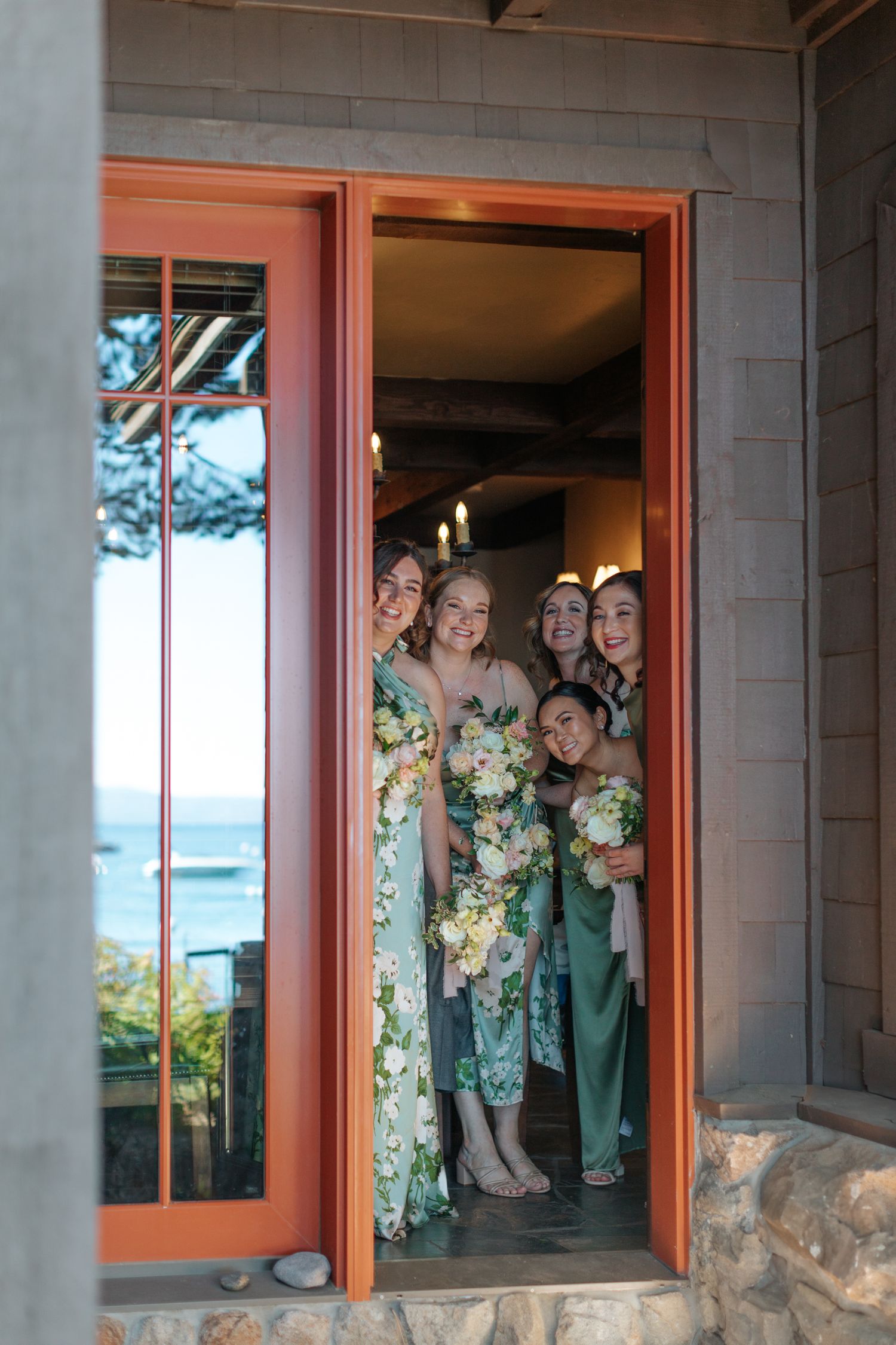 A group poses together in a window frame of a modern building with orange trim.