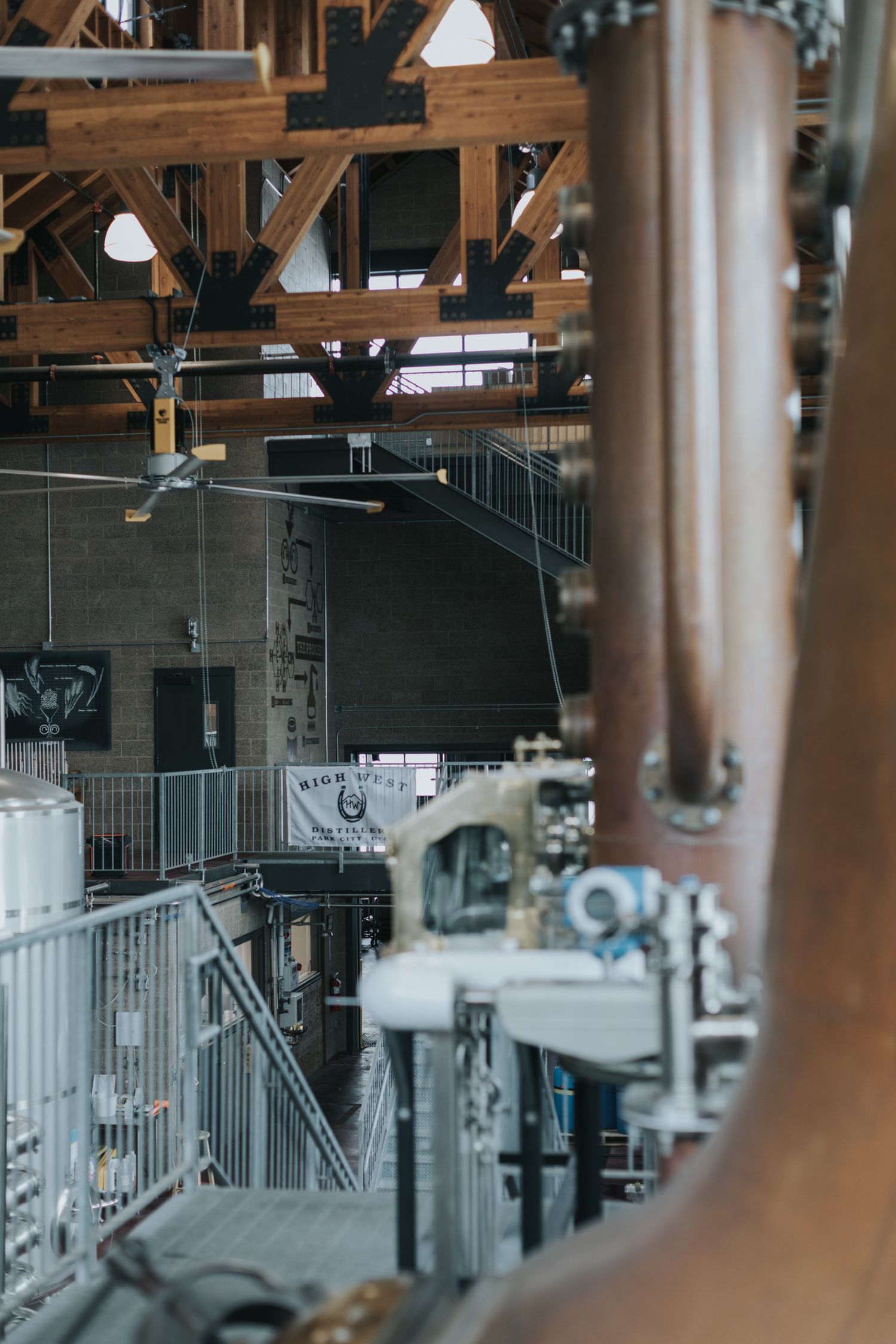 Modern distillery interior featuring tall copper stills and industrial equipment.