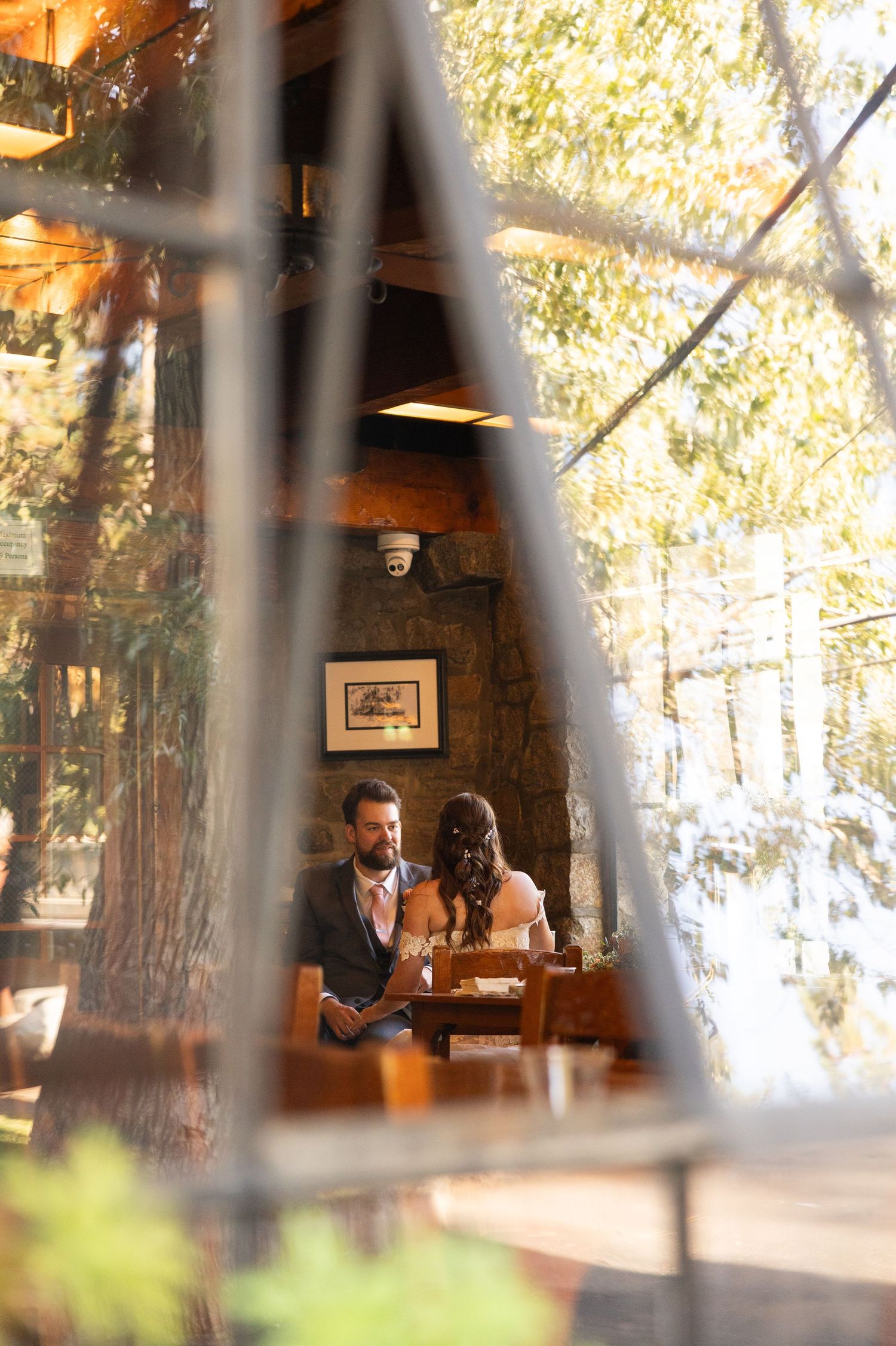Artistic wedding photo taken through window panes showing a rustic cabin interior.
