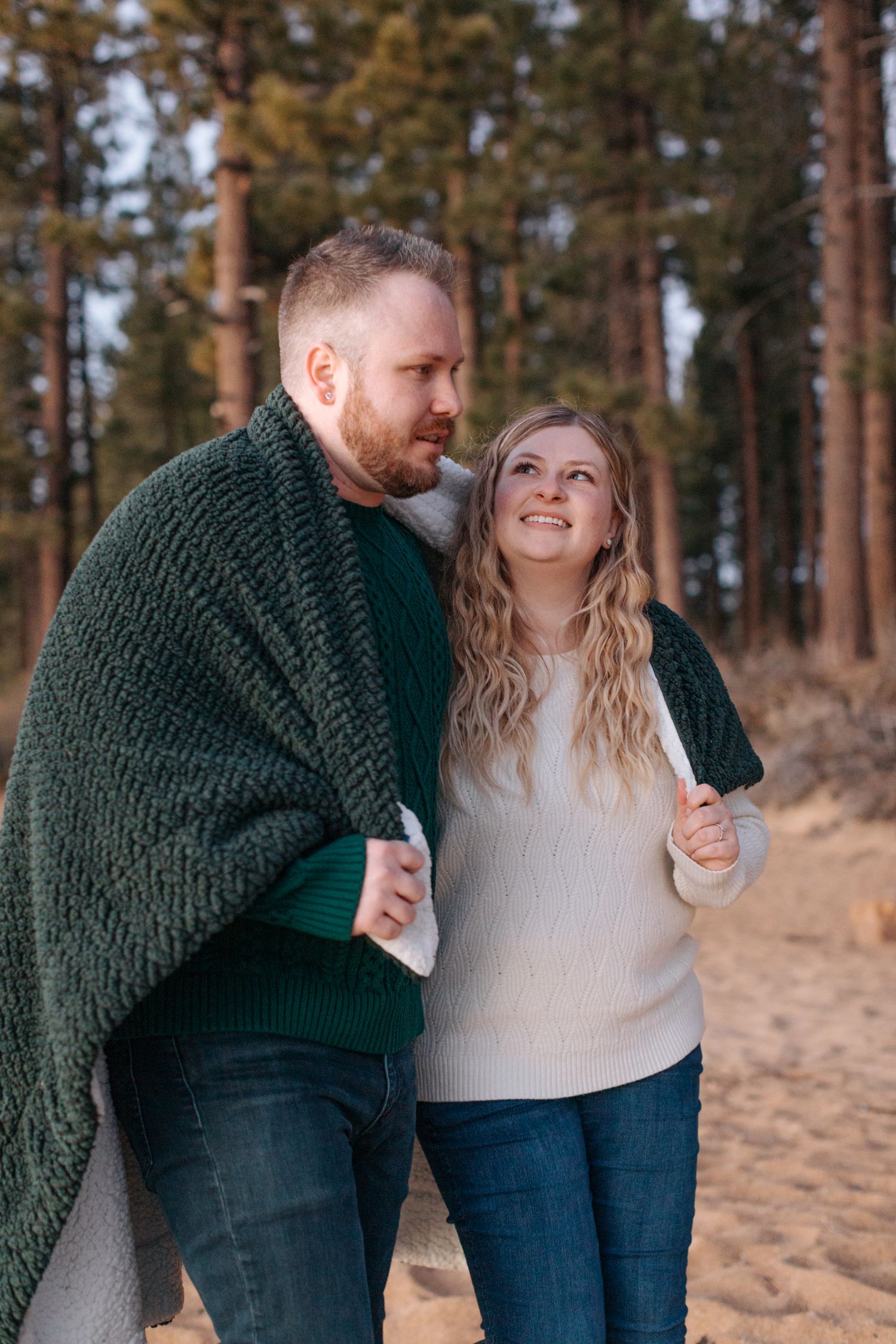 Playful couple photos in forest setting wearing coordinated winter outfits.
