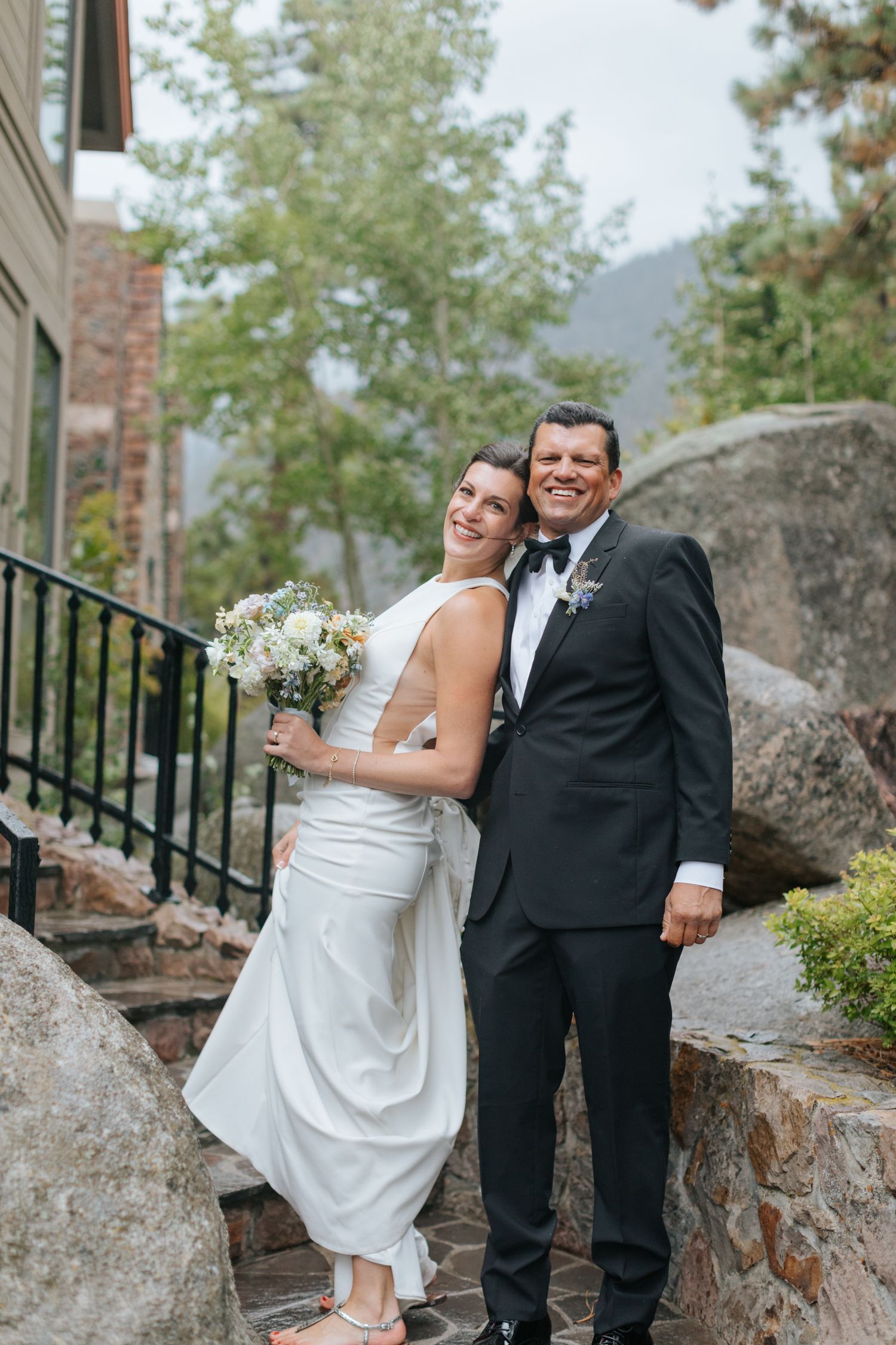 Elegant wedding couple posing on stone steps of historic building.