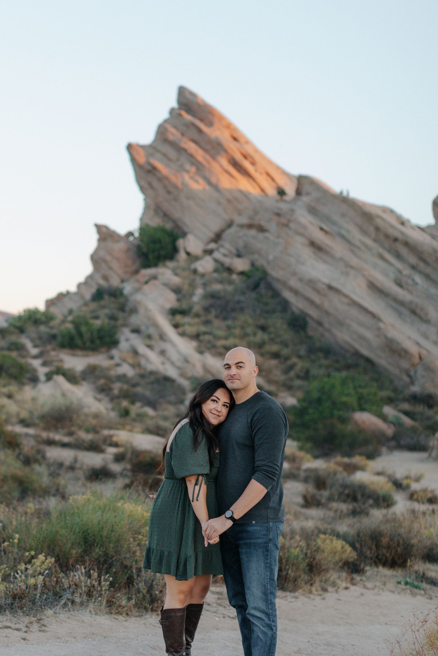 Romantic desert photoshoot with dramatic rock formations in the background at golden hour.