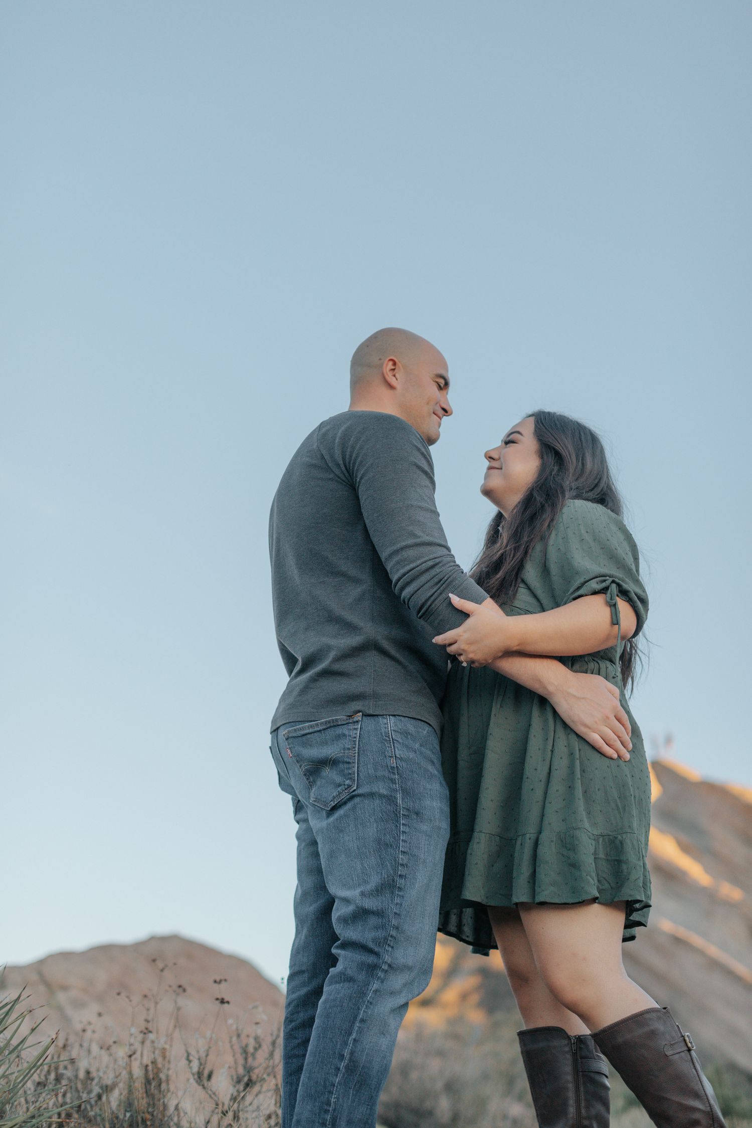 Two people share a tender moment on a desert trail during golden hour.