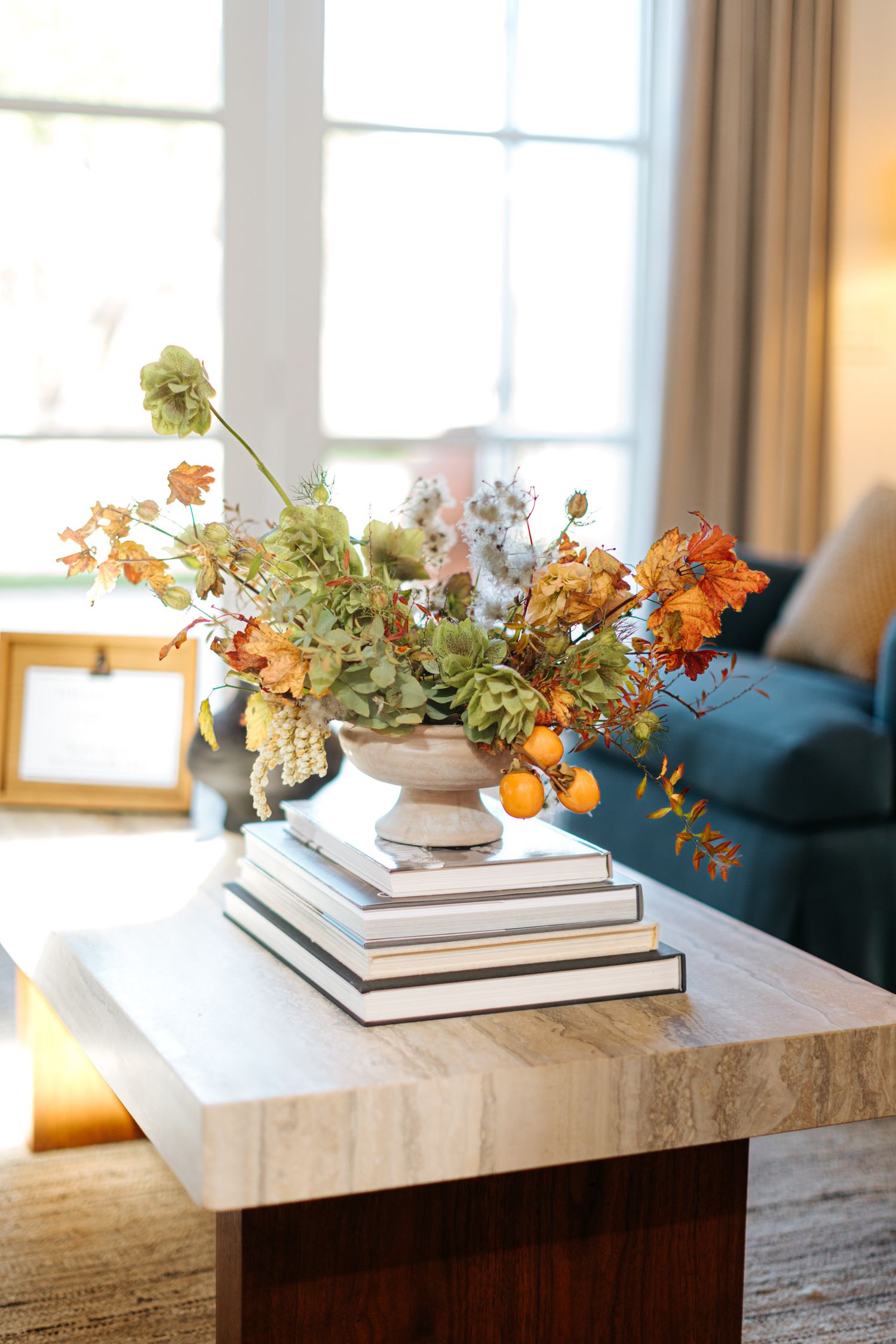 Modern coffee table styling with stacked books and floral arrangement in natural light.