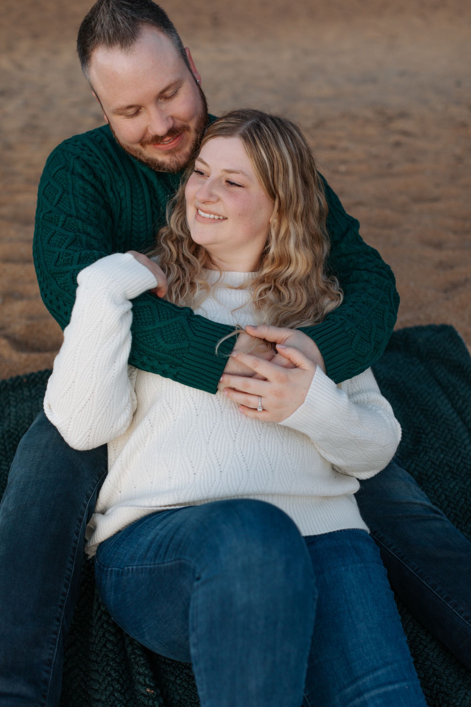 Intimate moments captured on a beach with cozy winter sweaters and casual attire.