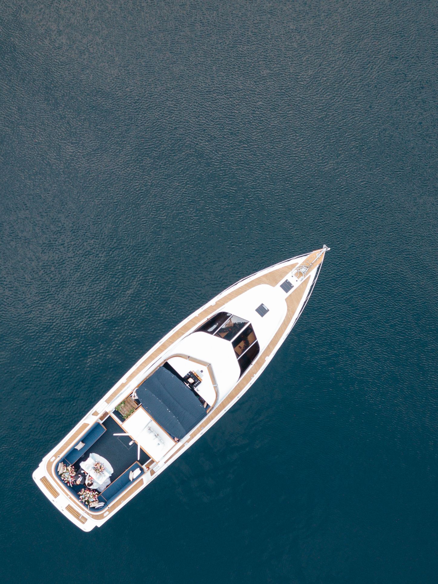 Aerial view of white yacht cruising on deep blue waters.