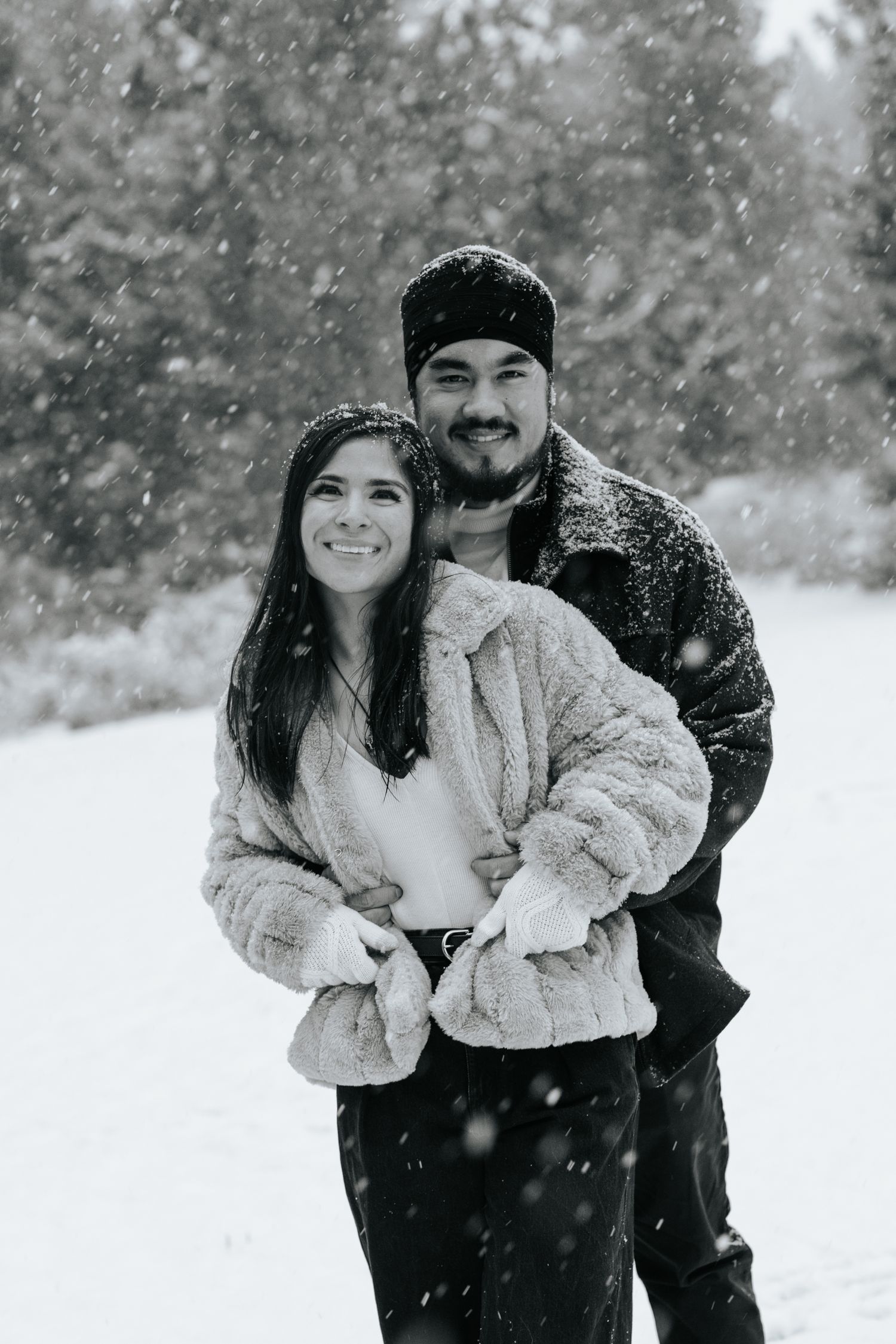 Playful couple enjoying a snowy day wearing winter coats and beanies.