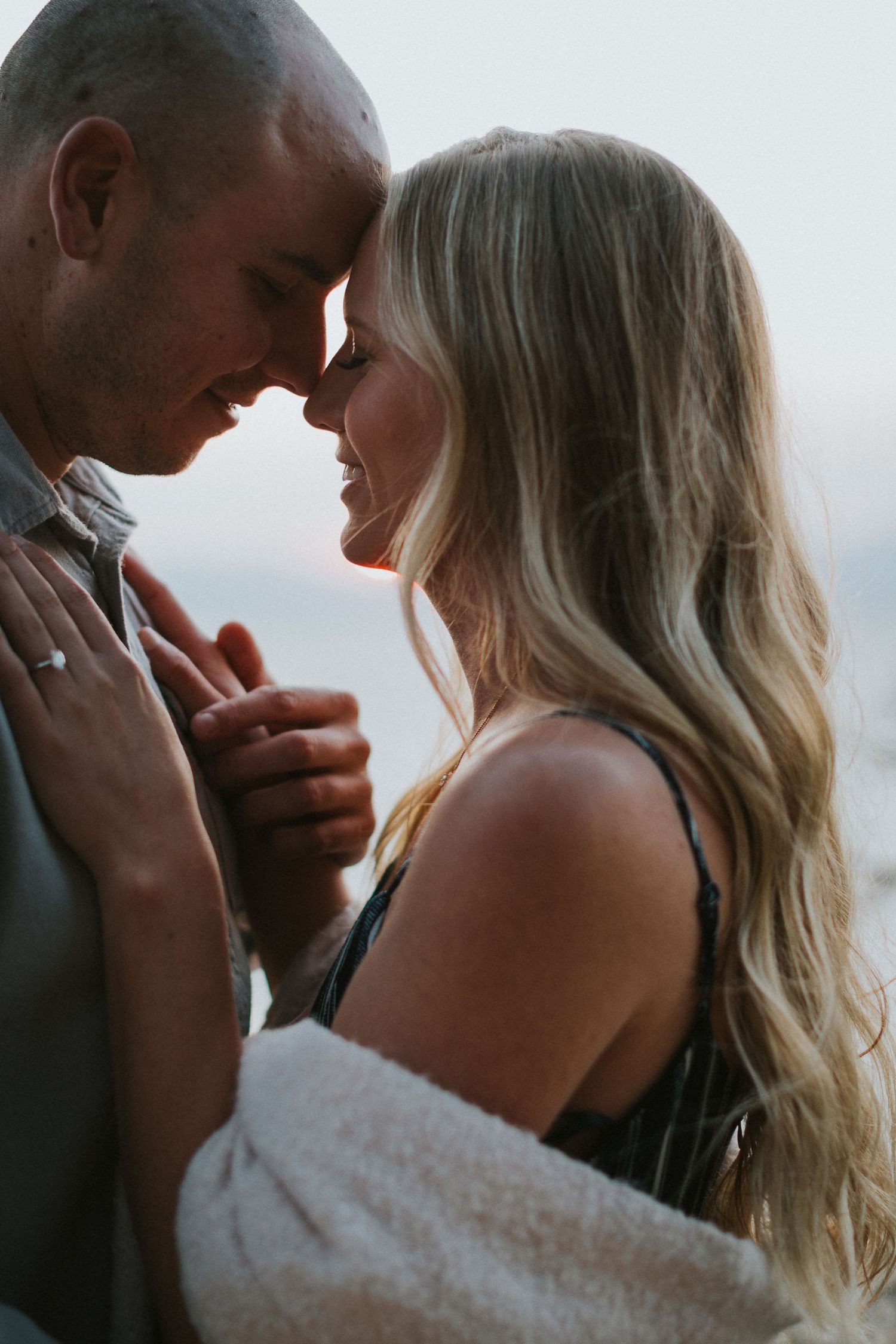 Intimate close-up portrait of a couple sharing a tender moment against a light background.