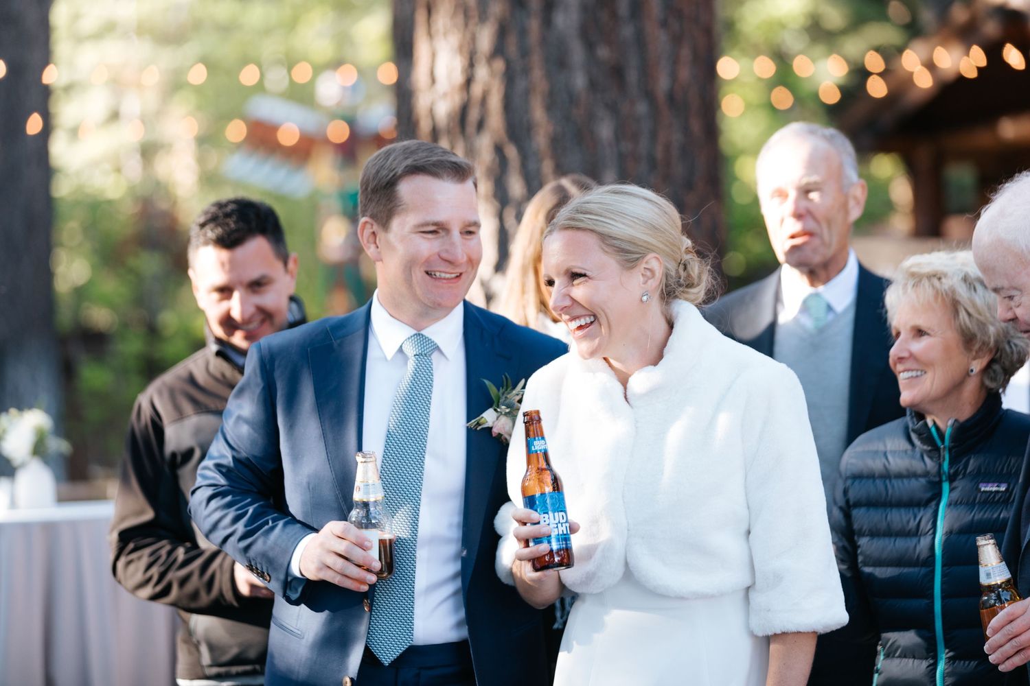 Guests mingle and chat at a wedding reception in an outdoor venue with natural lighting.