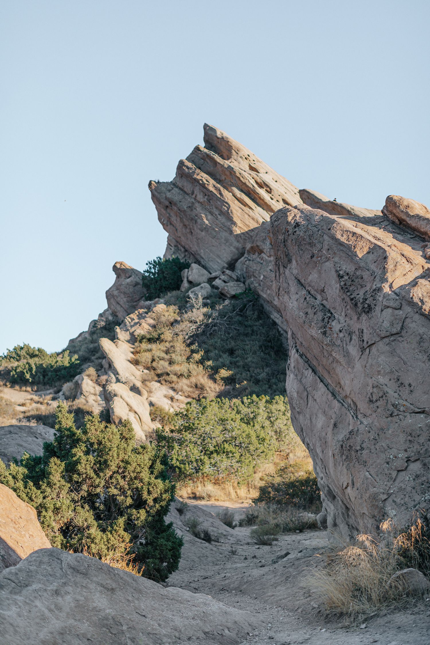 Rugged desert rock formations rise against a clear blue sky.