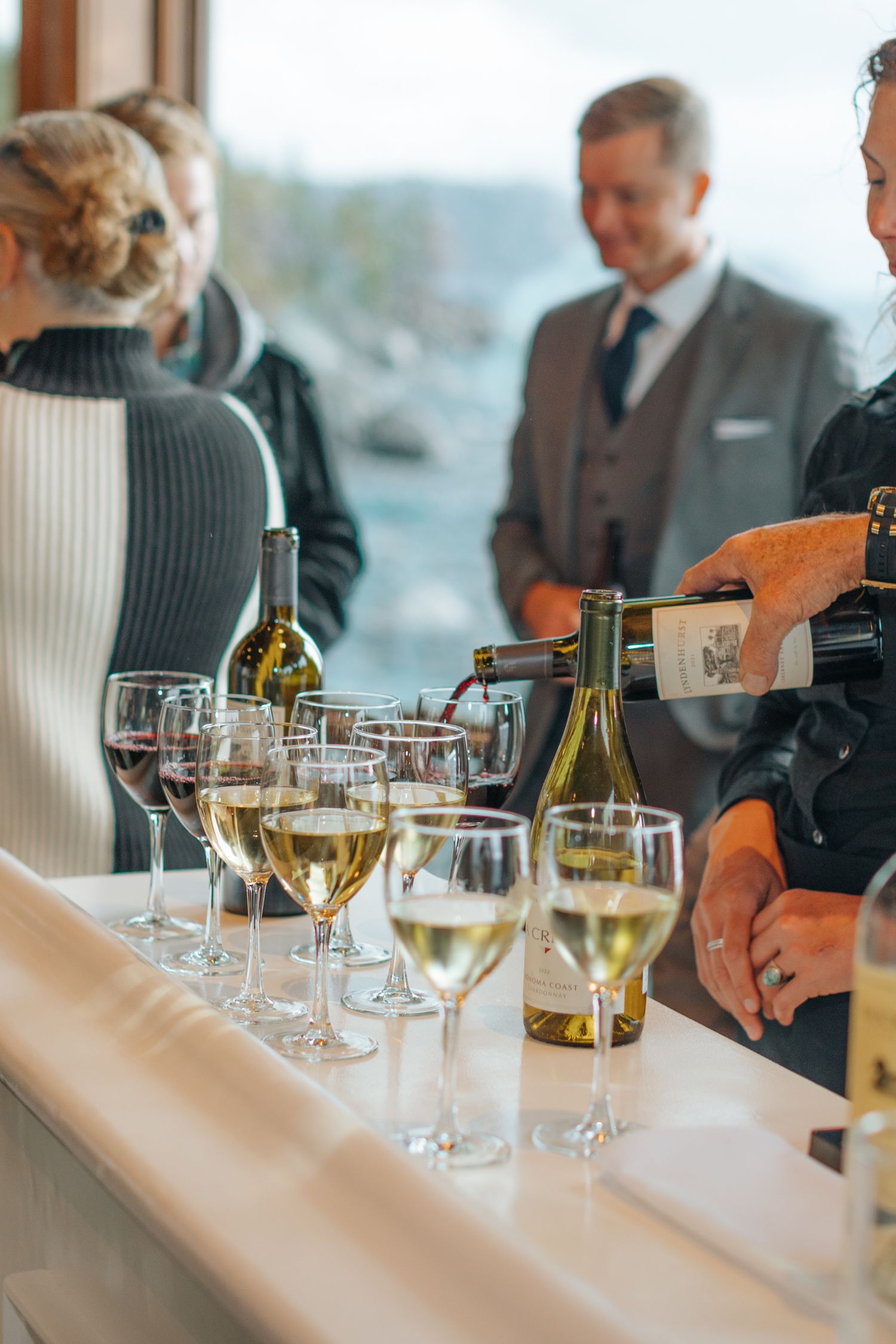 Wine glasses and bottles arranged on an elegant dining table at an upscale event.