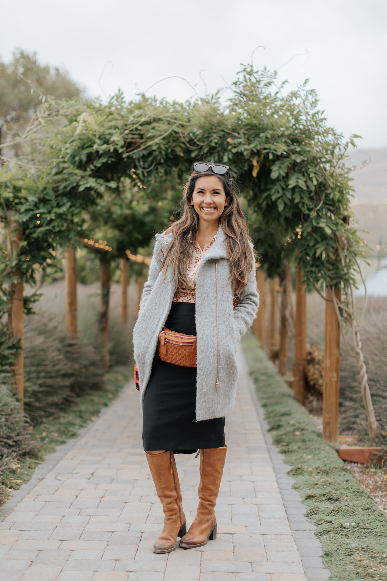 Garden pathway lined with wooden posts and hanging greenery in an outdoor venue setting.
