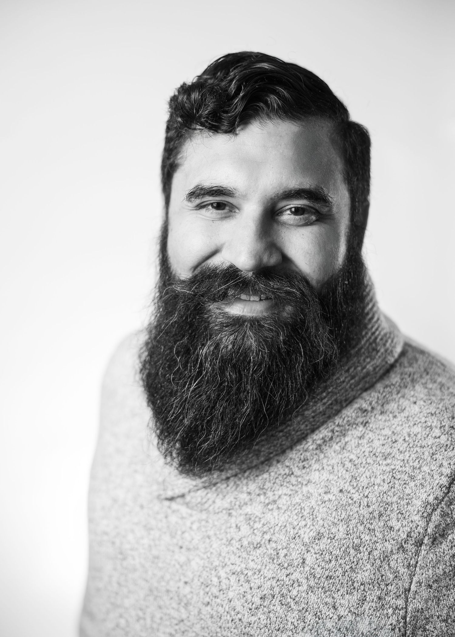 A black and white portrait series showing different angles of a man with a thick full beard wearing a sweater.