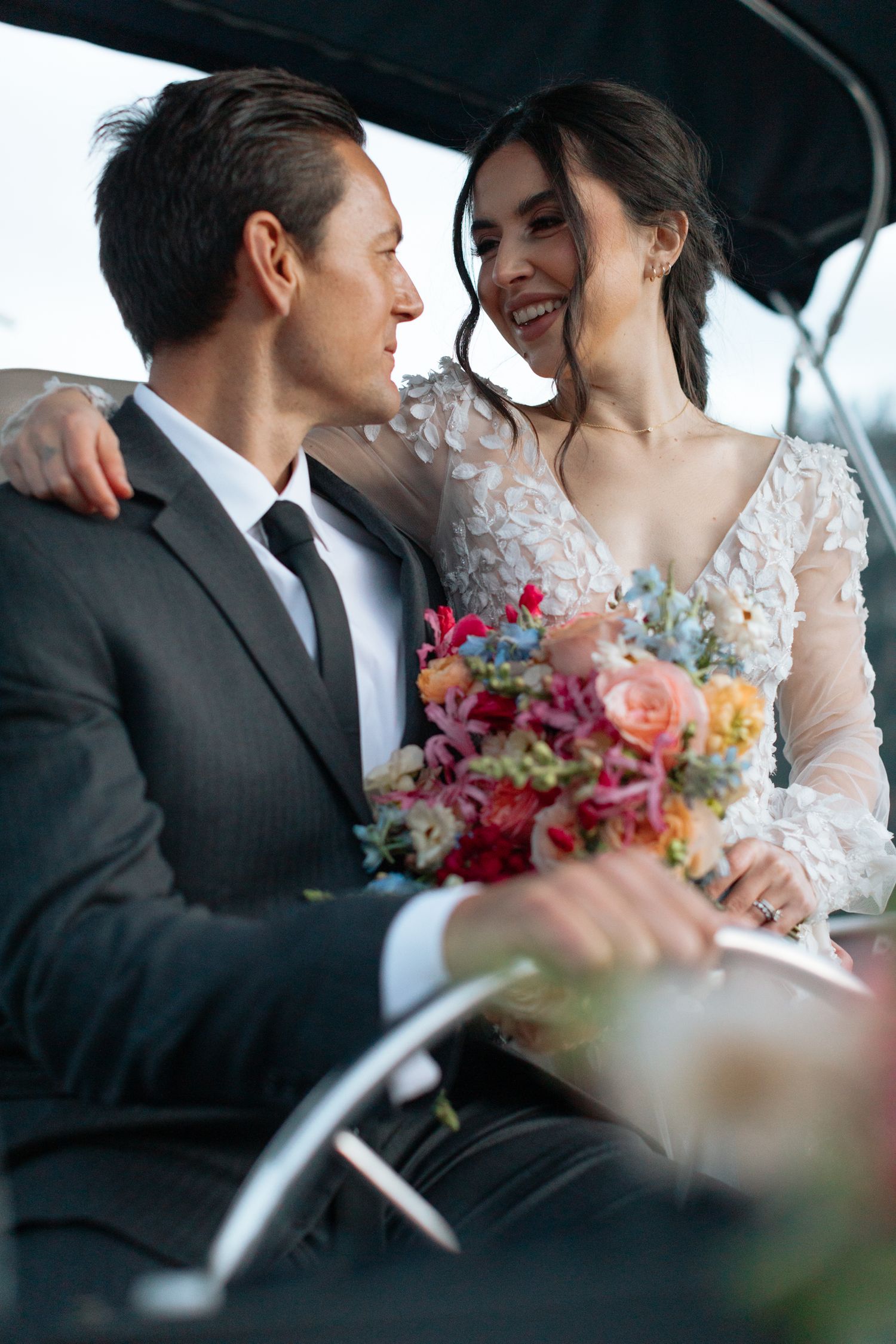 Intimate moment captured of newlyweds sitting together with a colorful bouquet on a boat.
