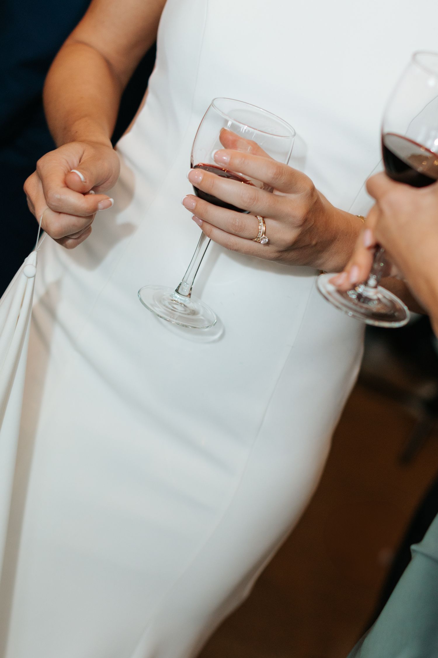 Close-up view of hands holding wine glasses against a white background.