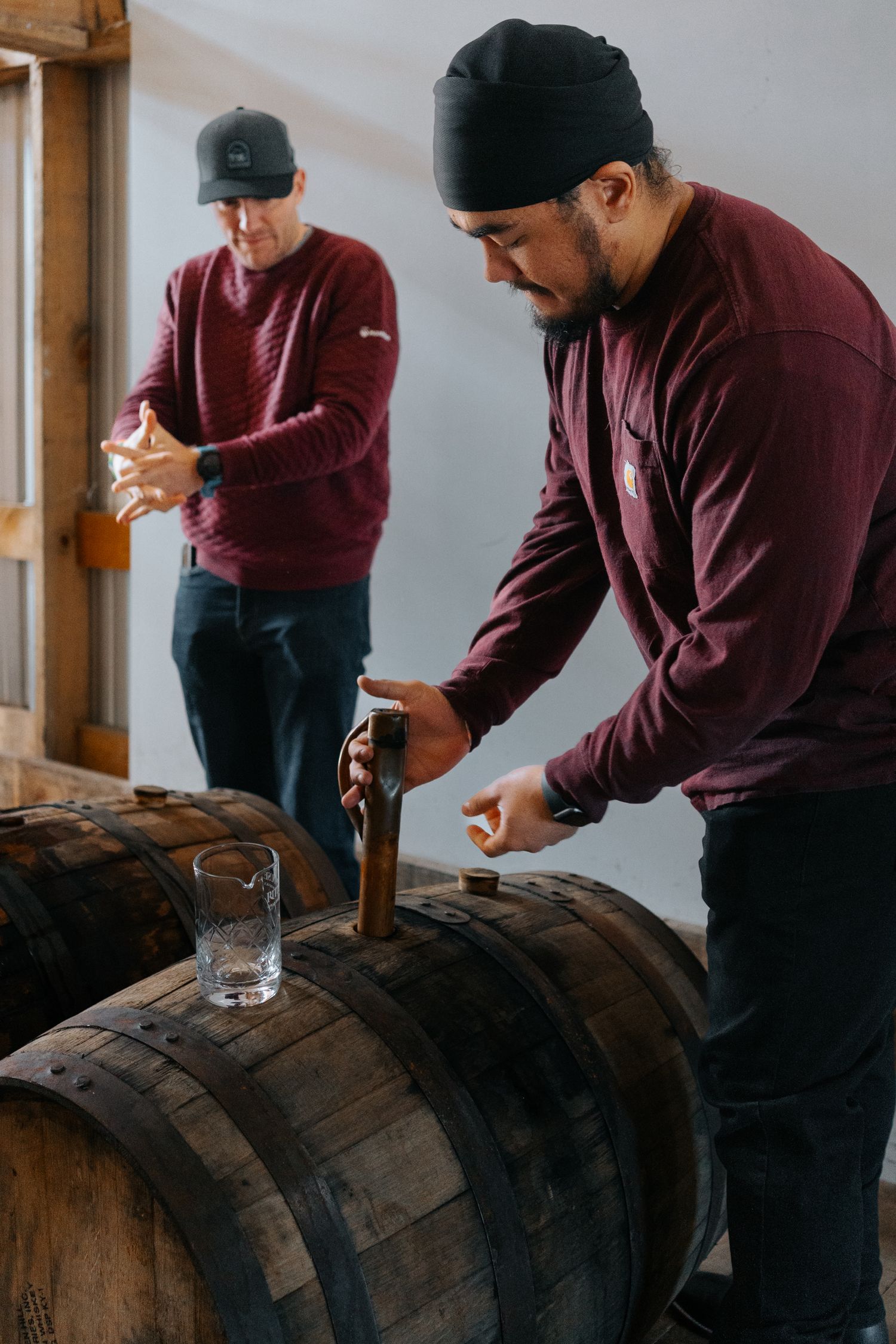 Distillery worker taking samples from a bourbon barrel.