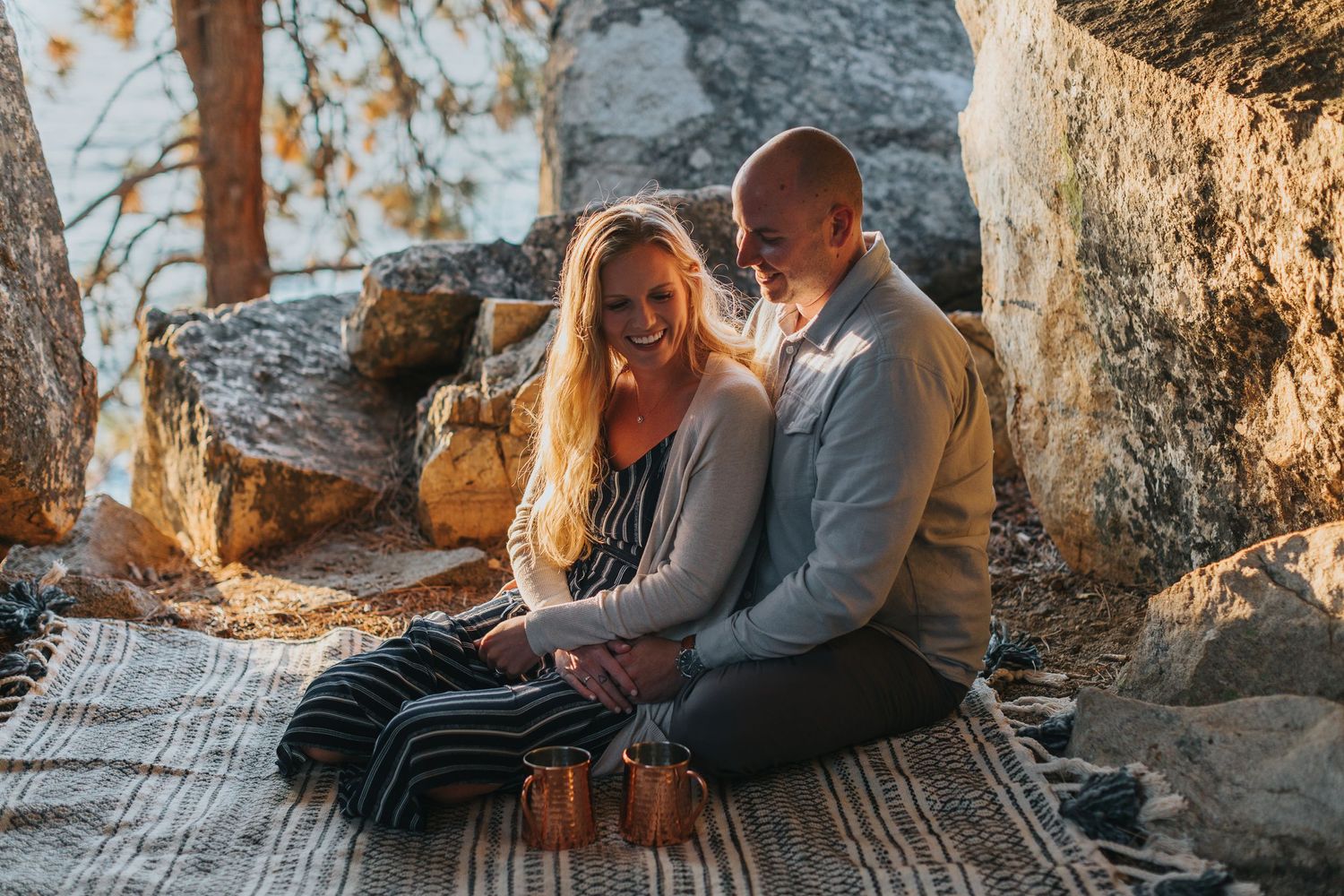 Couple sharing tender moment while relaxing on patterned blanket outdoors.
