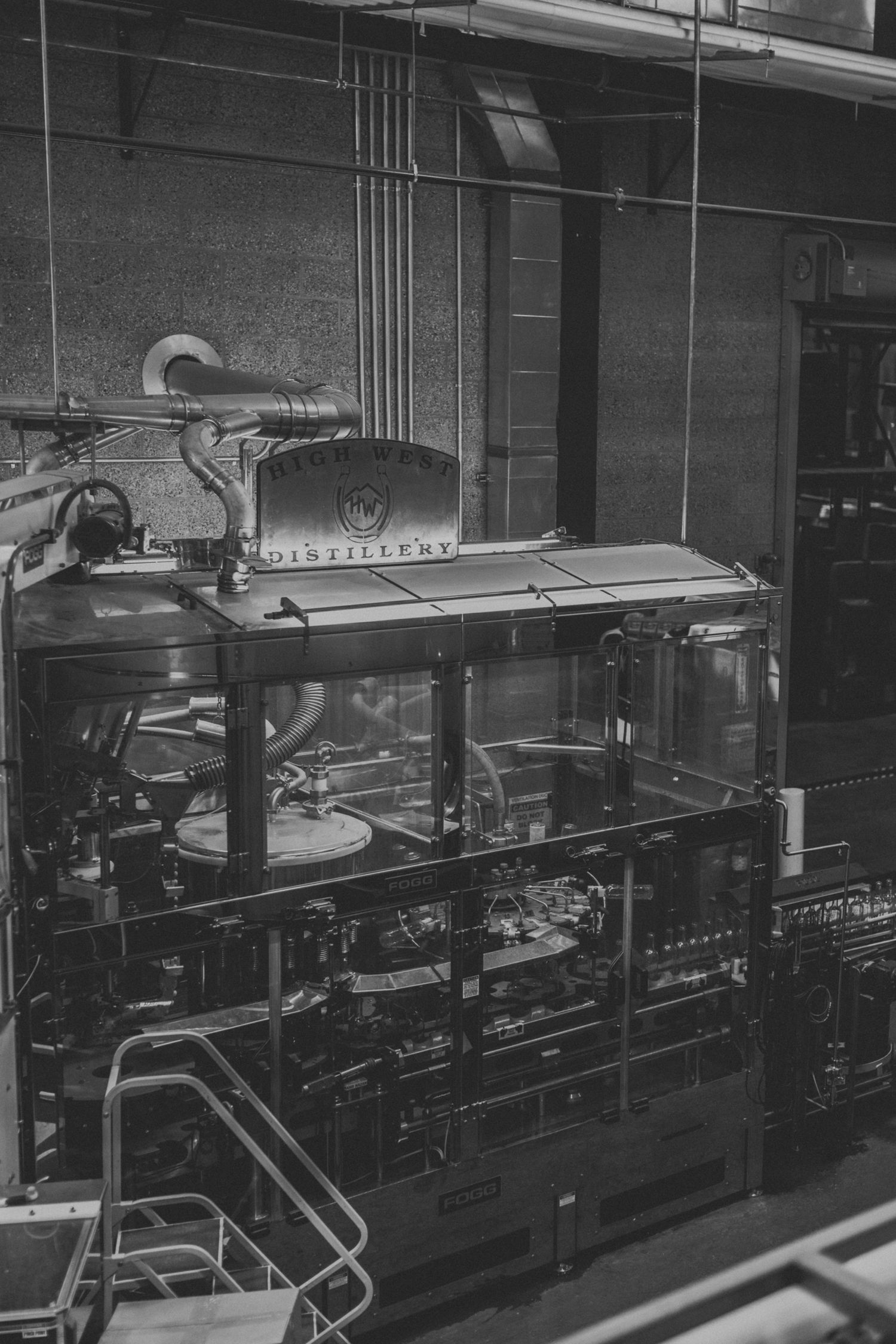 Industrial distillery equipment and machinery in dark monochromatic setting.
