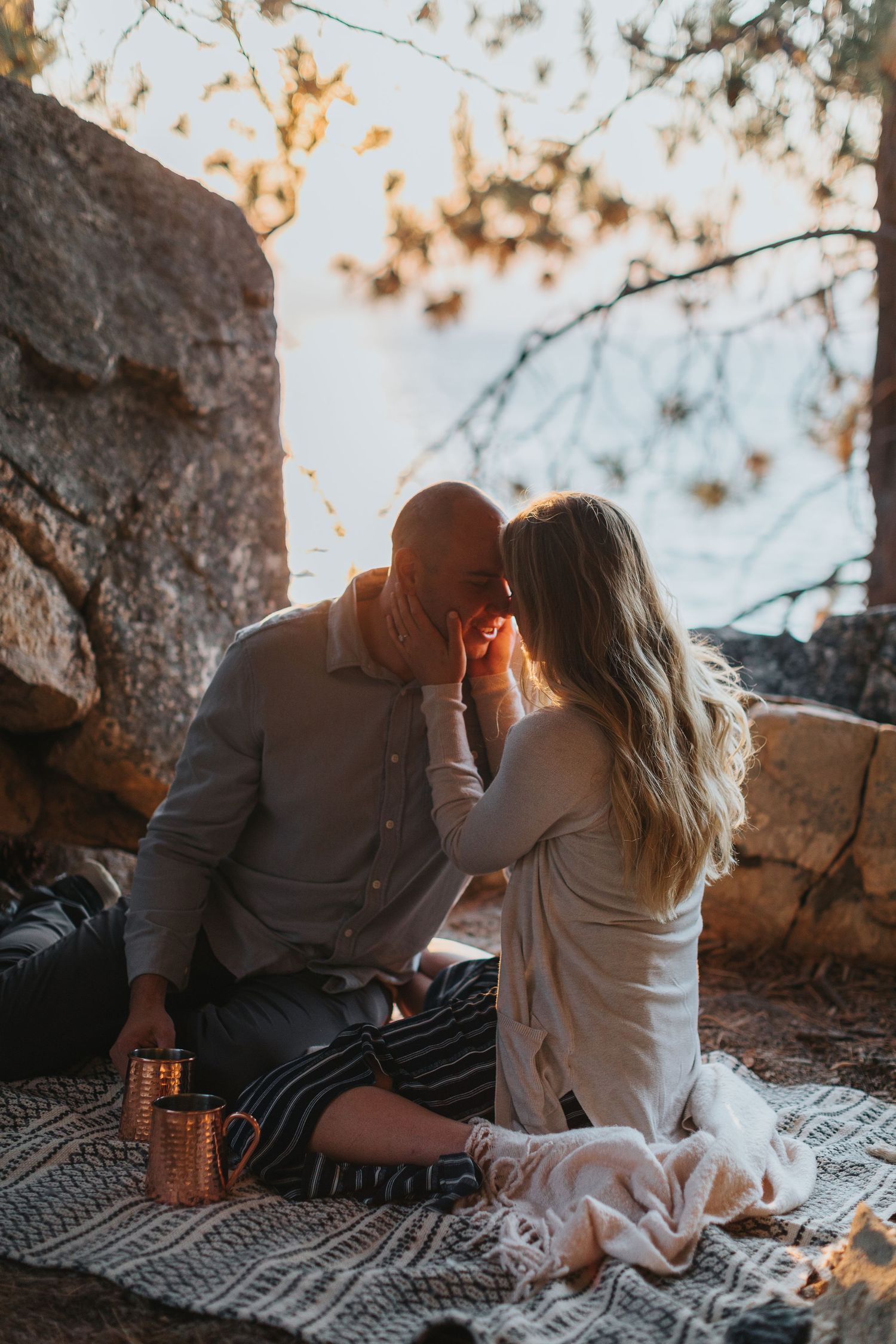 Romantic couple sitting on picnic blanket at sunset enjoying intimate moments in nature.