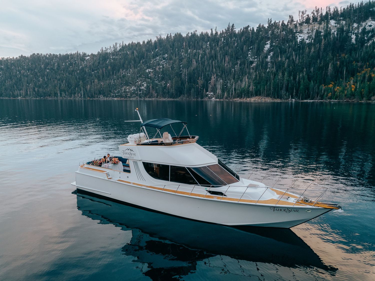 Scenic mountain lake view with luxury yacht silhouetted against forested shoreline.