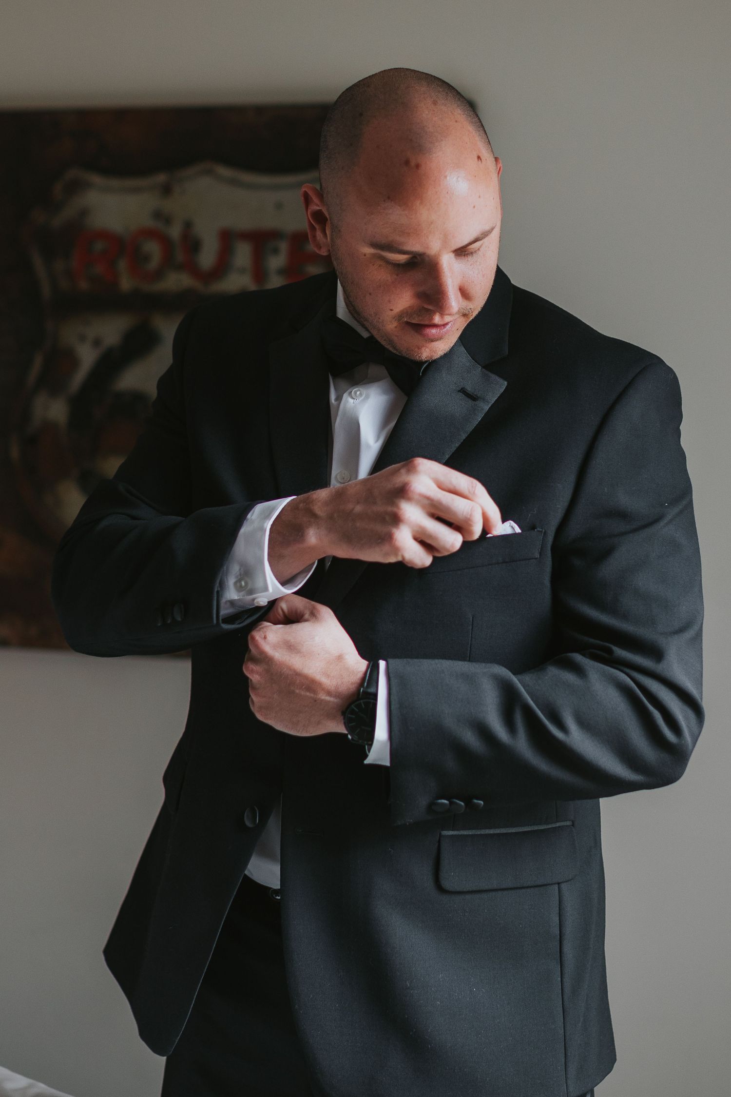Person in dark suit adjusting formal wear before event.