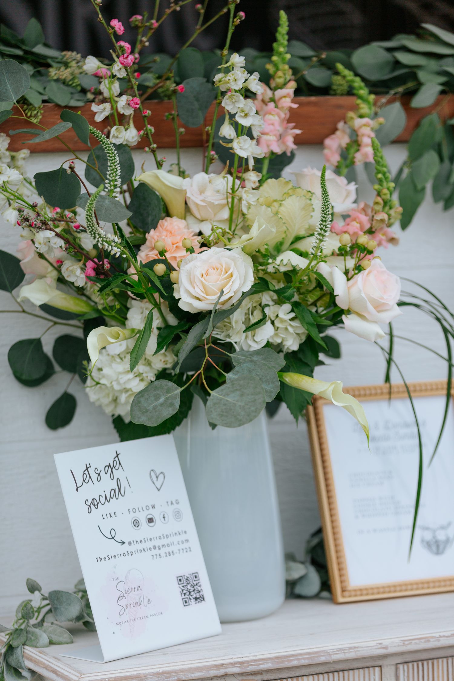 Elegant floral arrangements with roses and greenery alongside framed wedding details.
