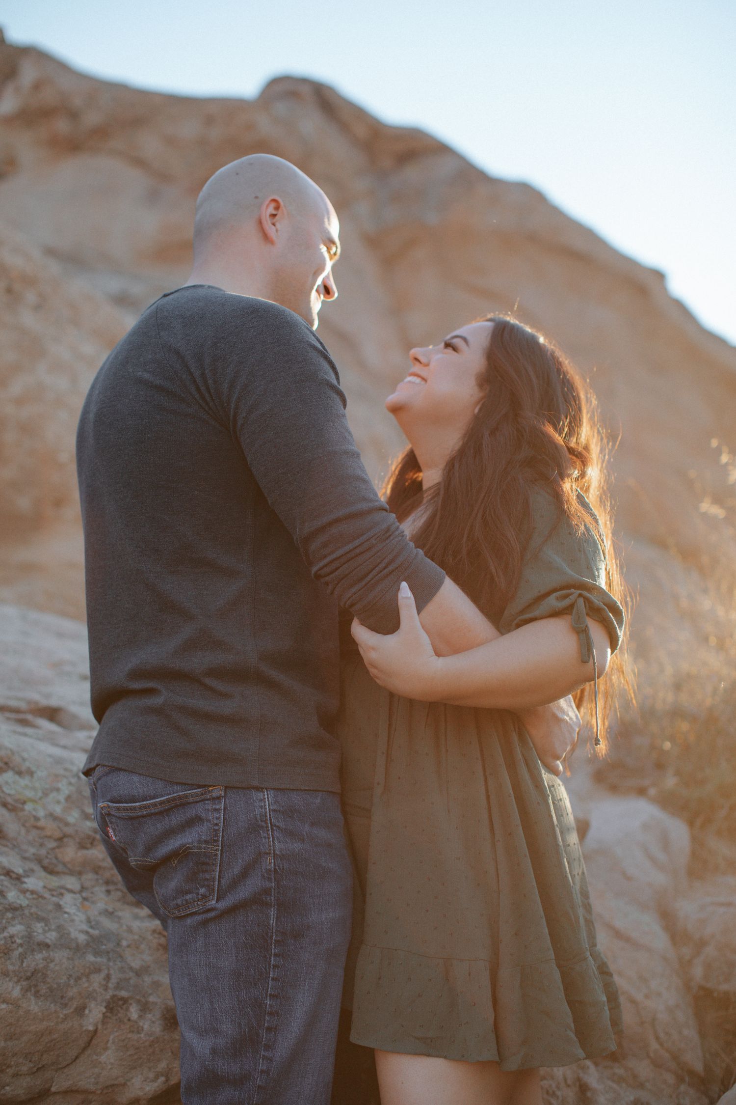 A romantic couple shares an intimate moment against desert cliffs at sunset.