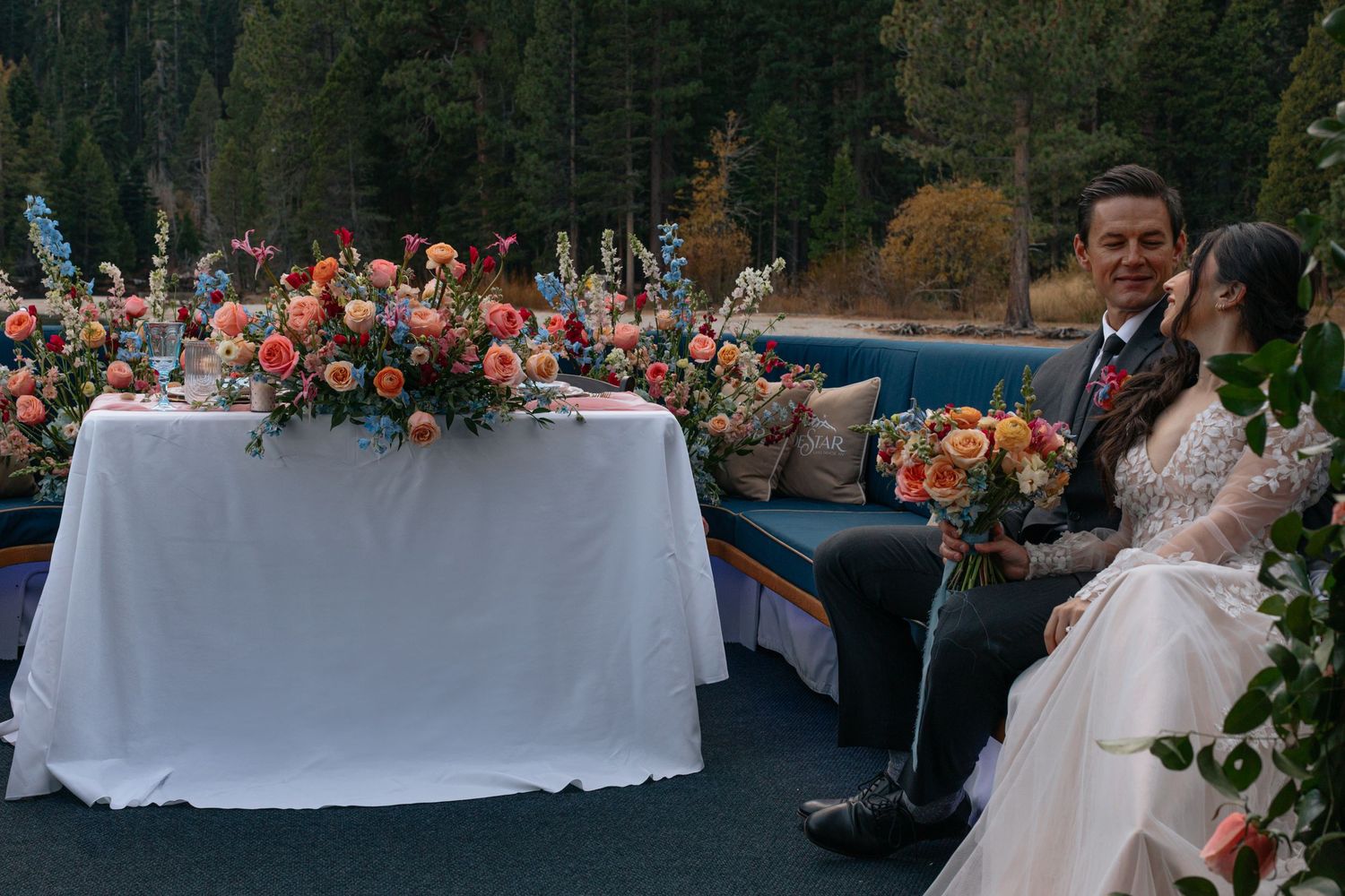 Wedding celebration on boat deck with elegant table setting and floral arrangements.