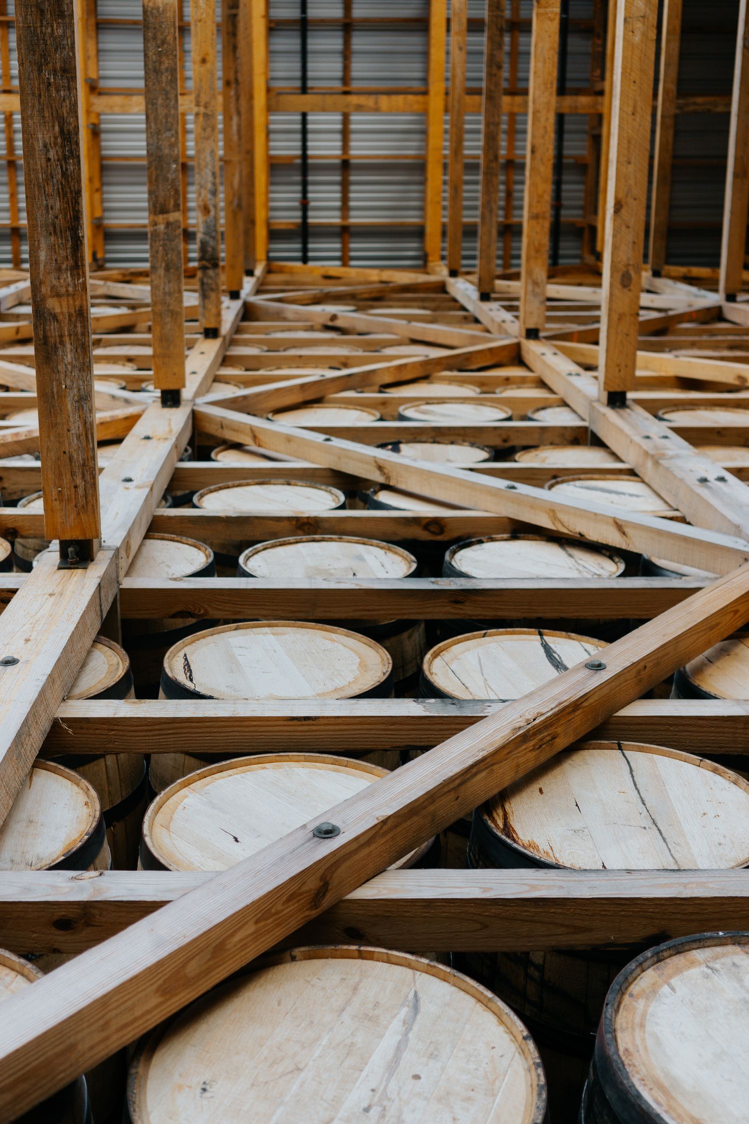 Rows of wooden barrel racks in a traditional whiskey aging warehouse.