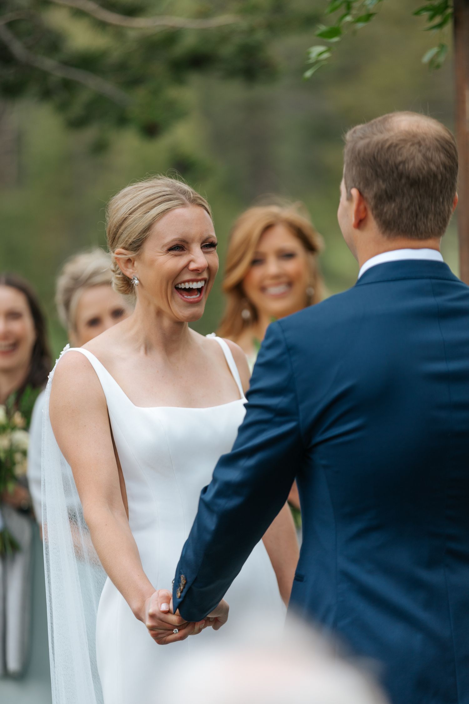 A joyful wedding ceremony moment captured outdoors with guests looking on in a natural setting.