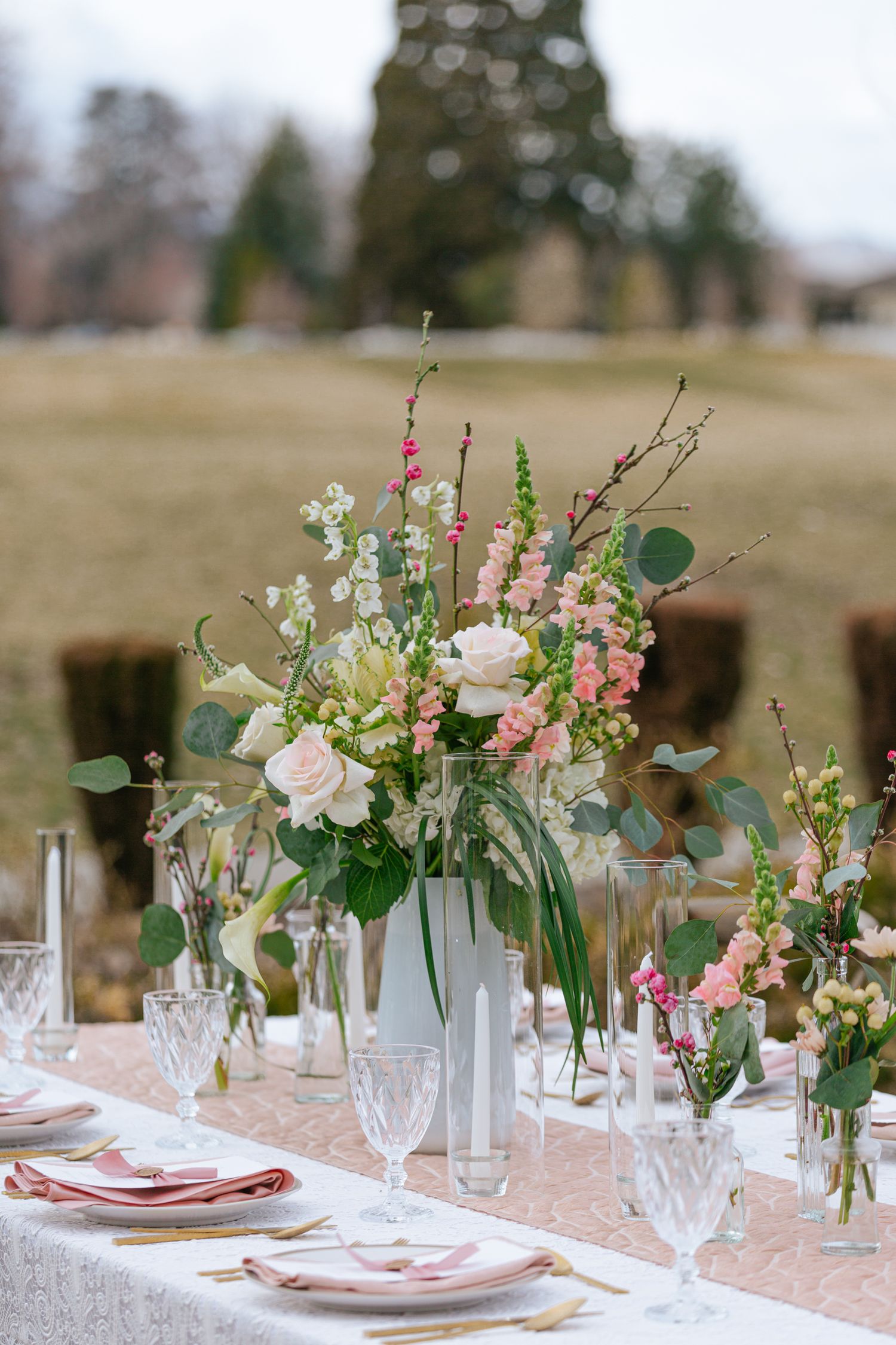 Elegant table setting with crystal glasses and pink floral centerpieces.