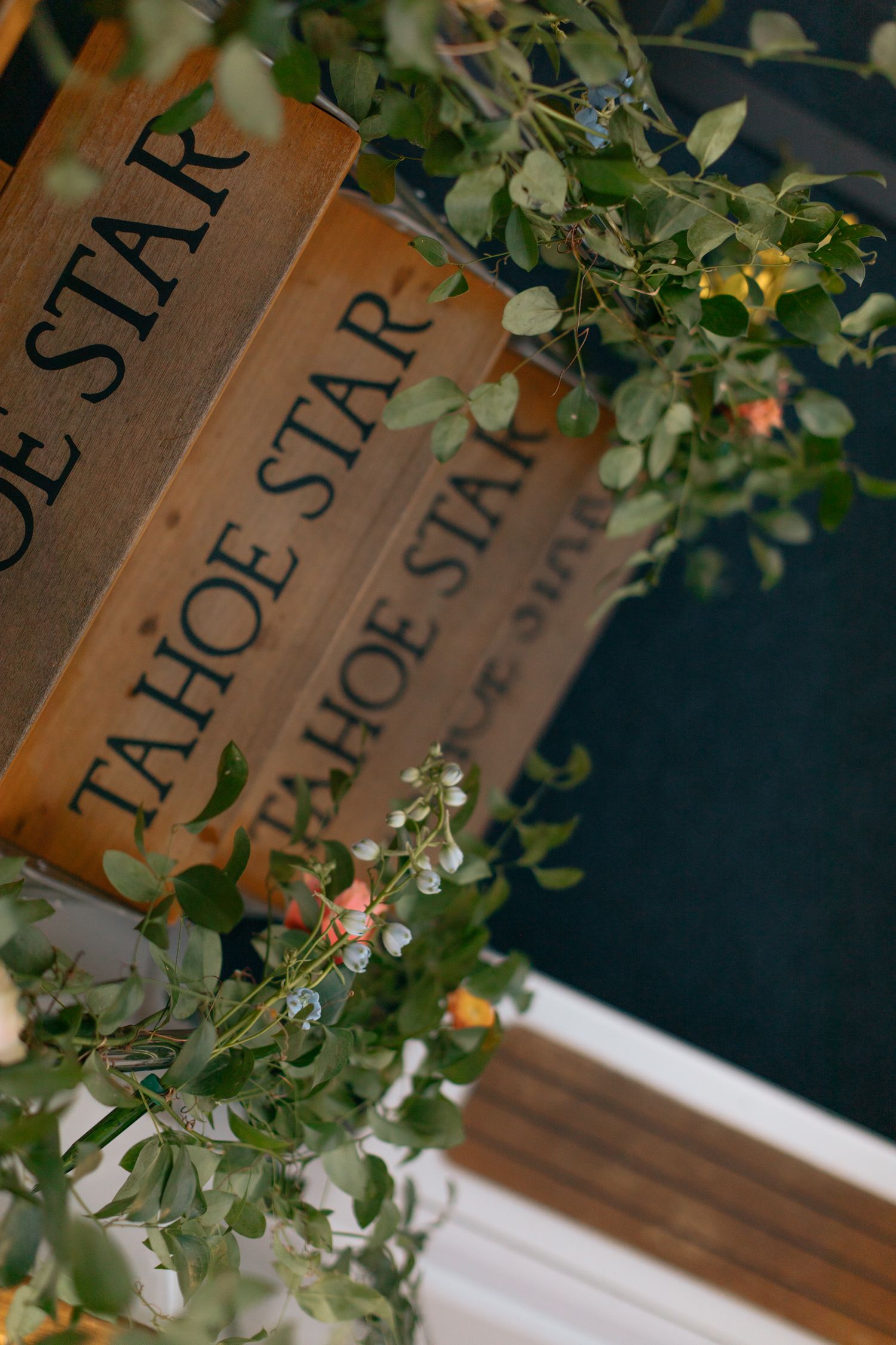 Wooden books with 'Tahoe Star' text decorated with delicate greenery and flowers.