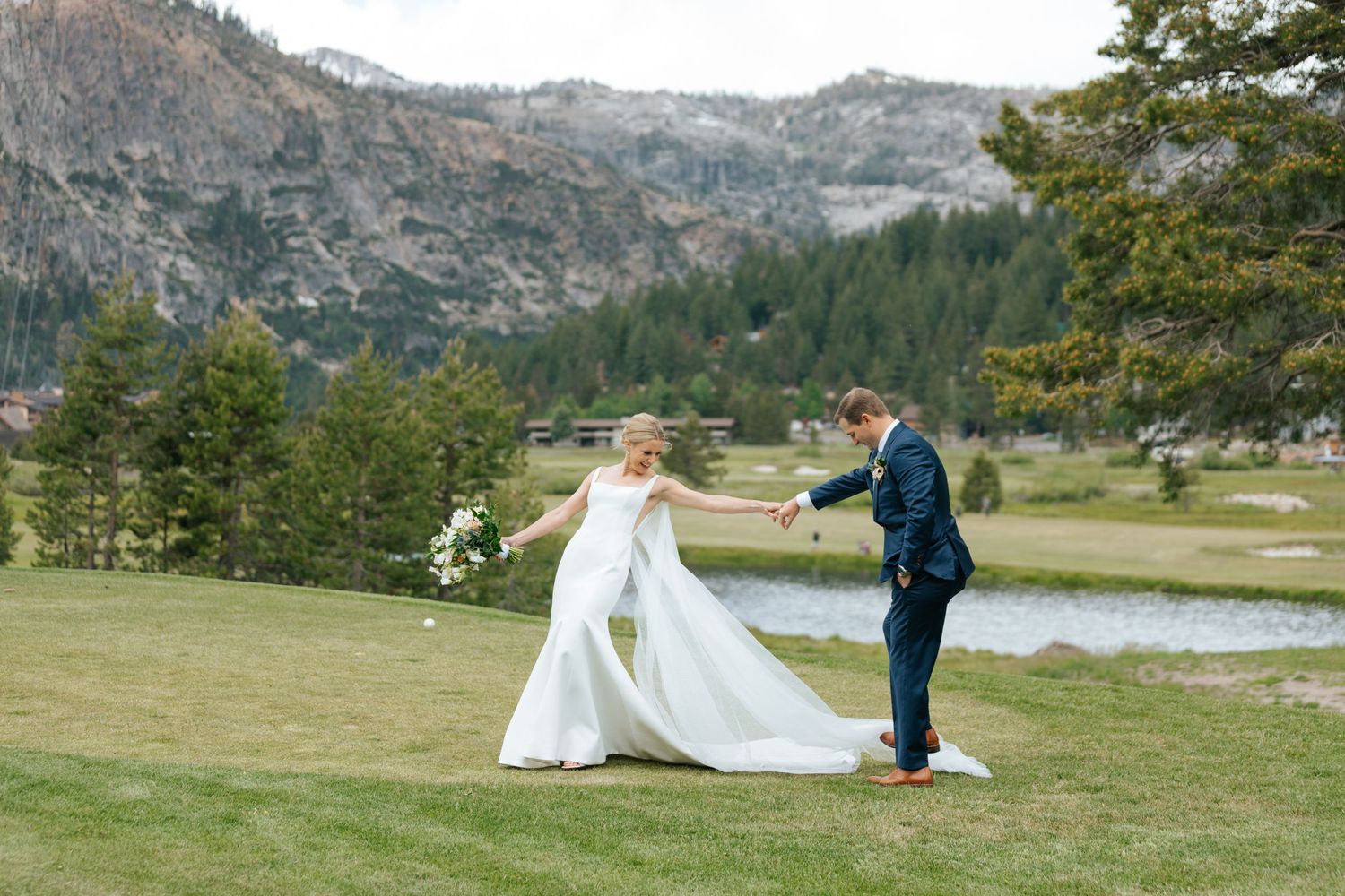 Bride and groom dancing on green lawn with mountain lake backdrop at outdoor wedding in Lake Tahoe.