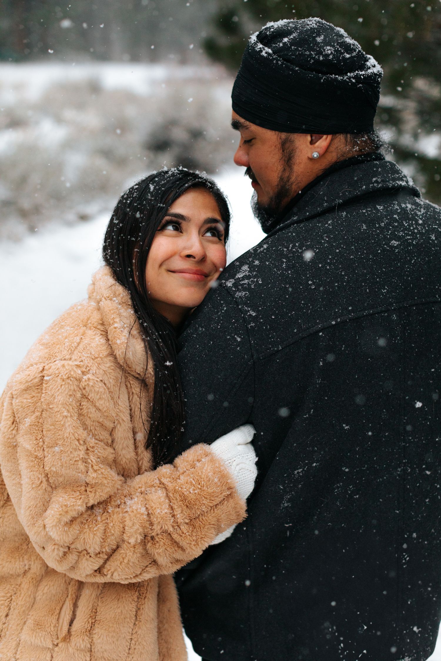 Intimate winter moment captured between couple in warm coats as snow falls.