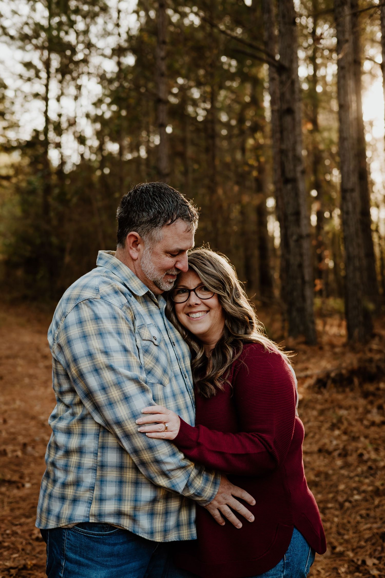 Happy couple embracing and smiling together on a forest path during a warm autumn day.