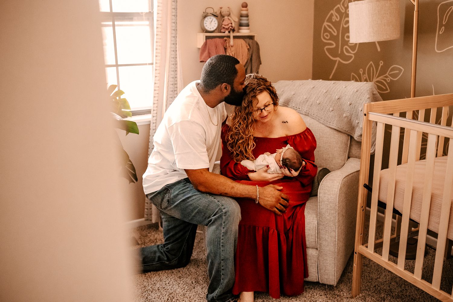 A loving couple admires their newborn baby together in a softly decorated nursery room.