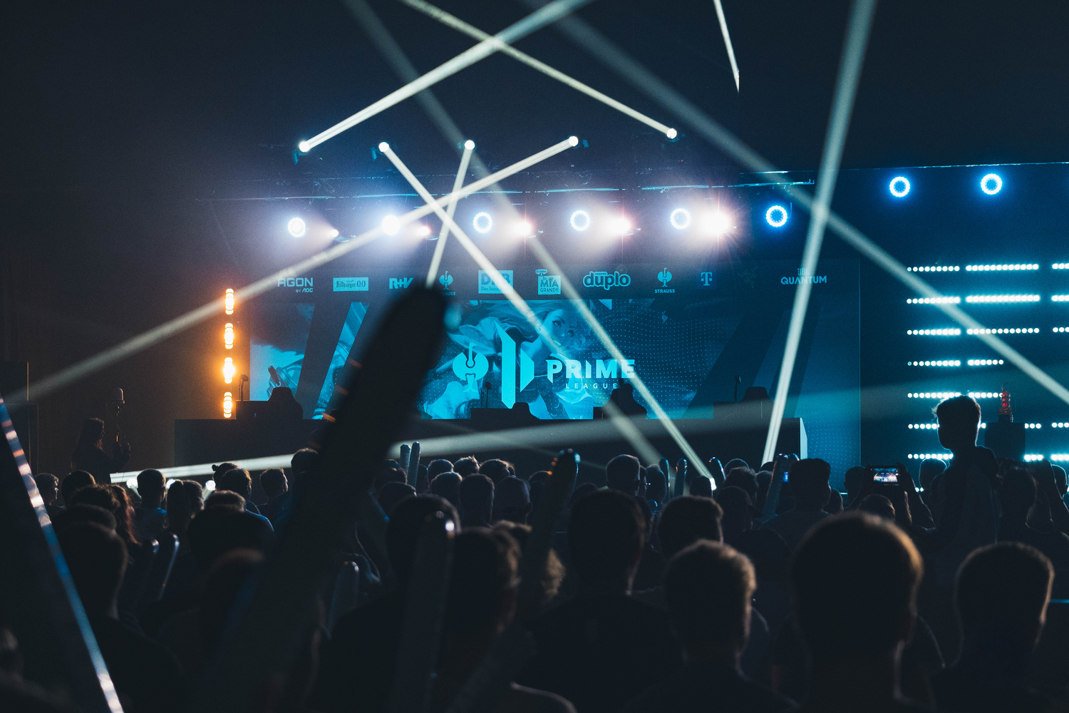 Crowd facing a stage with multiple spotlights and a large screen displaying 'PRIME' at the Strauss Primeleague esports tournament in Berlin.