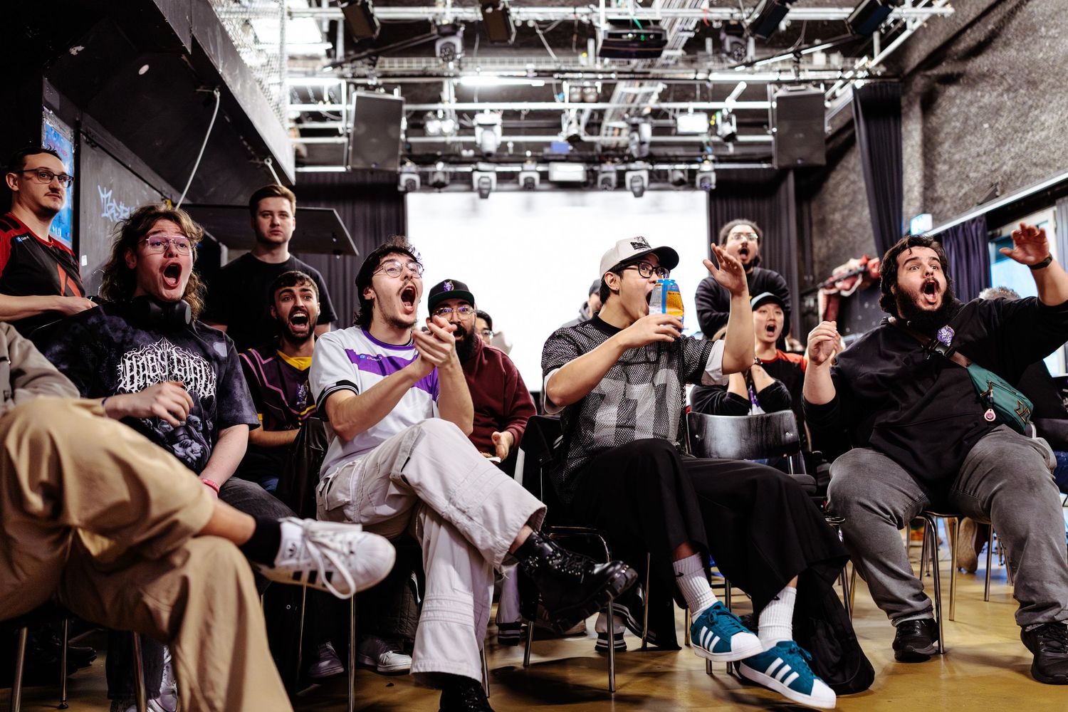 Bundesbattle Tekken finals audience cheering in rows, with fans shouting, raising their arms, clapping, and reacting excitedly to the match.