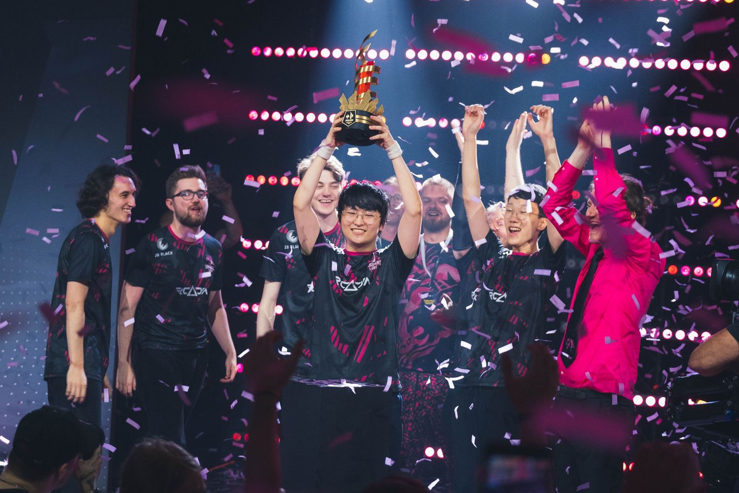Unicorns of Love Sexy Edition players in matching jerseys celebrate on stage as one lifts a trophy surrounded by falling confetti.