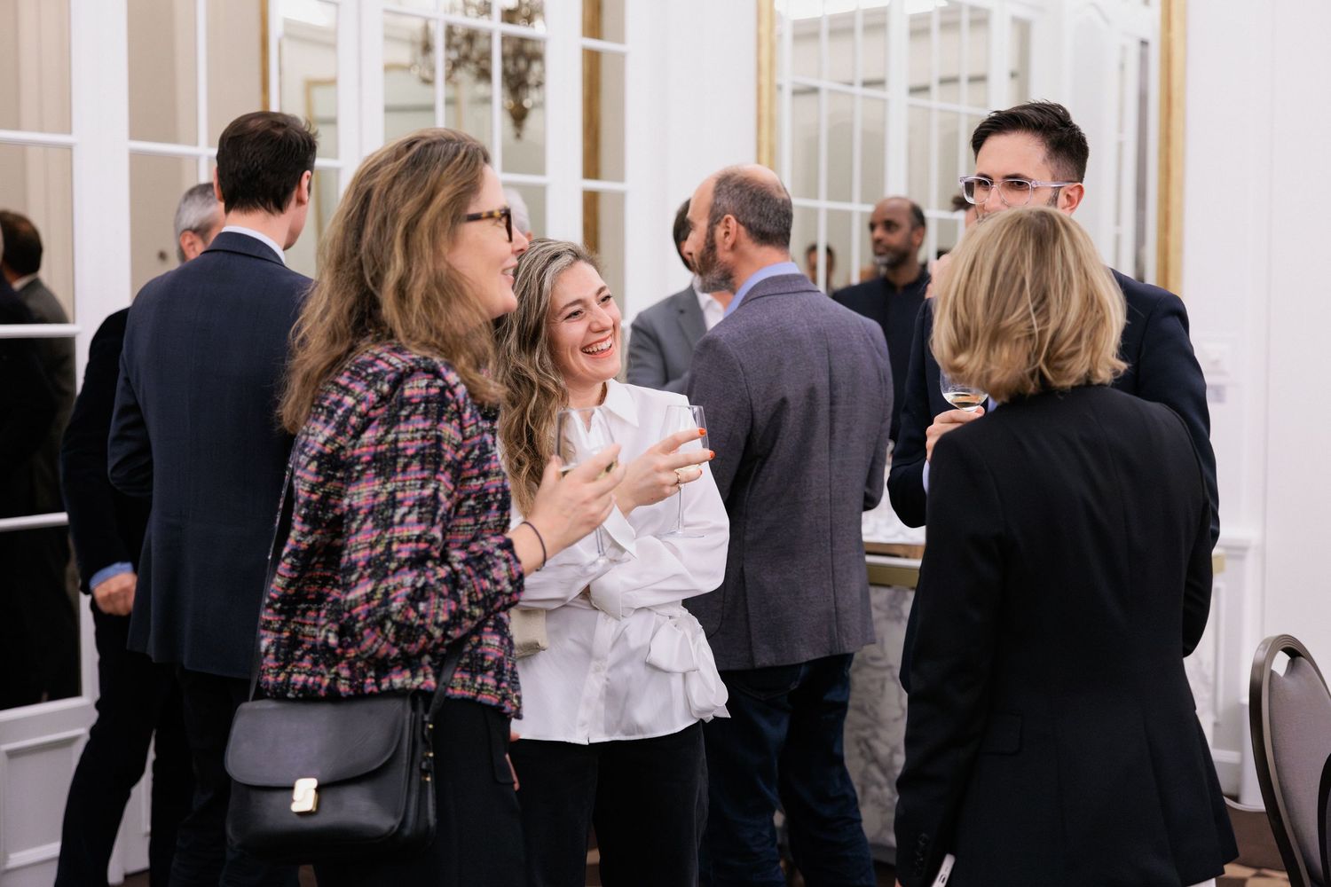 Professionals networking at a formal event, engaging in lively conversation in an elegant venue.