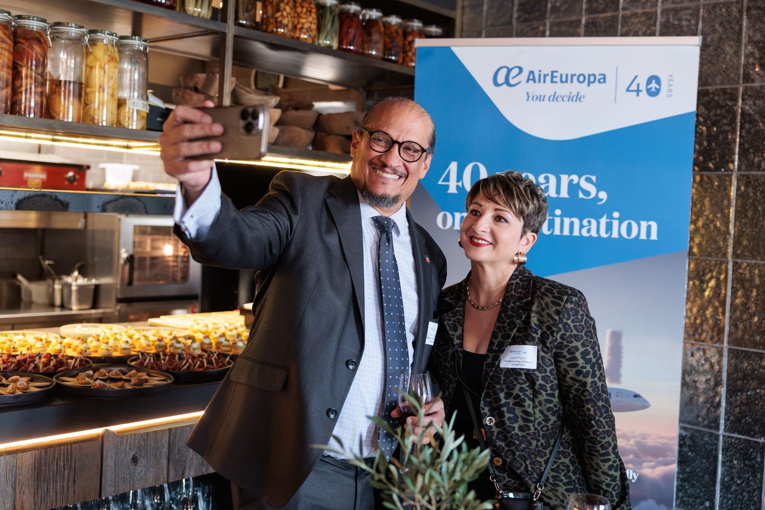 Two professionals take a selfie at Air Europa's 40th anniversary celebration event with branded banner.