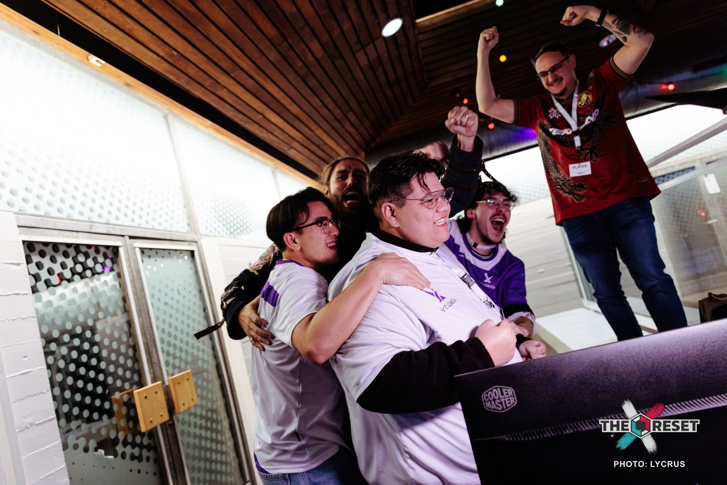 Esports team celebrating victory with hugs and cheers at a gaming tournament event.