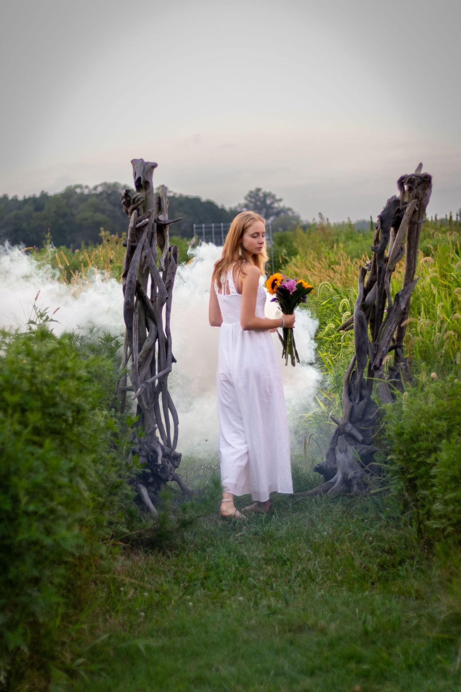 Creative outdoor portrait of a woman in a white dress among flowers