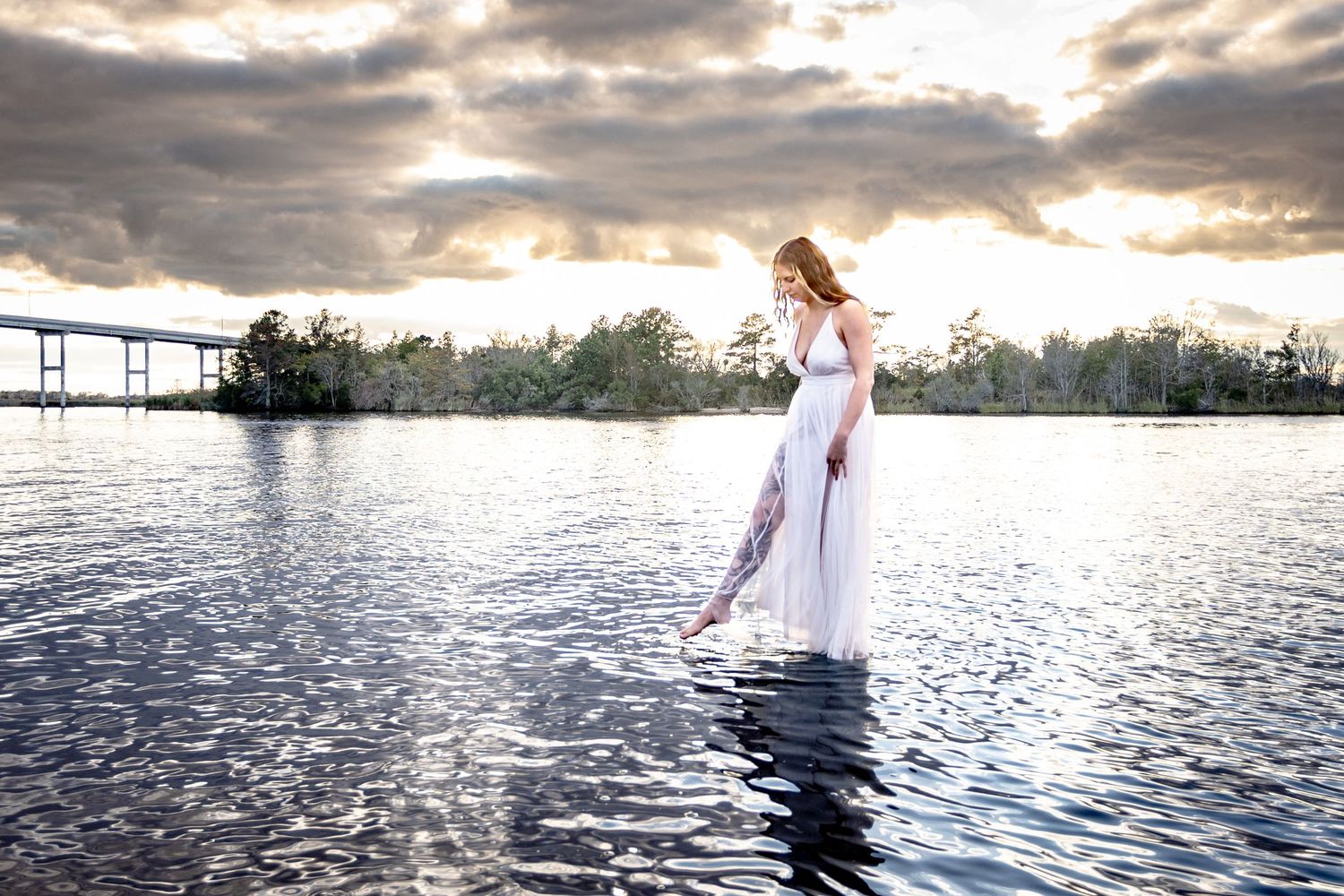 Creative portrait of a woman standing in the water at sunset