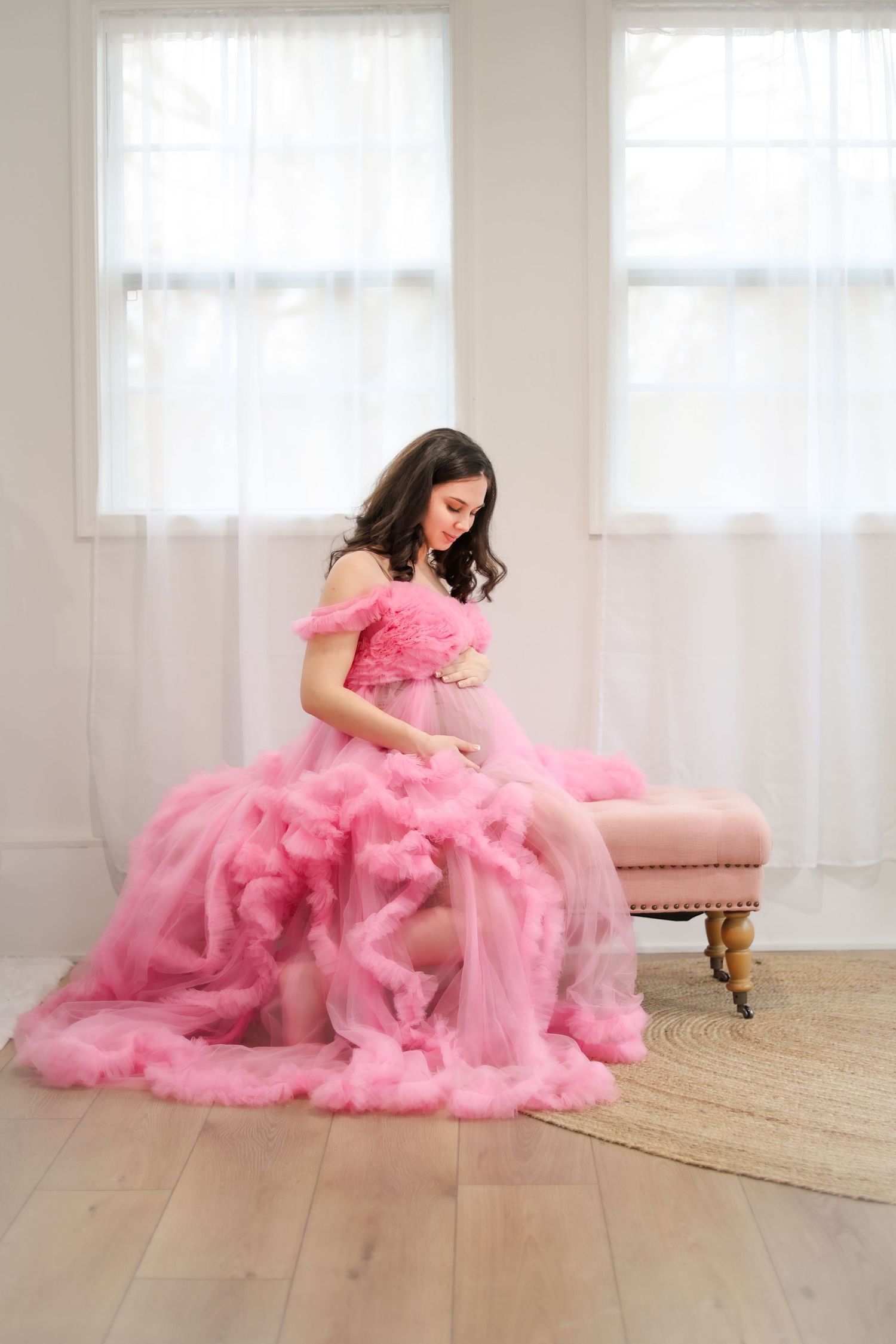 Creative maternity portrait in a pink gown in a bright studio
