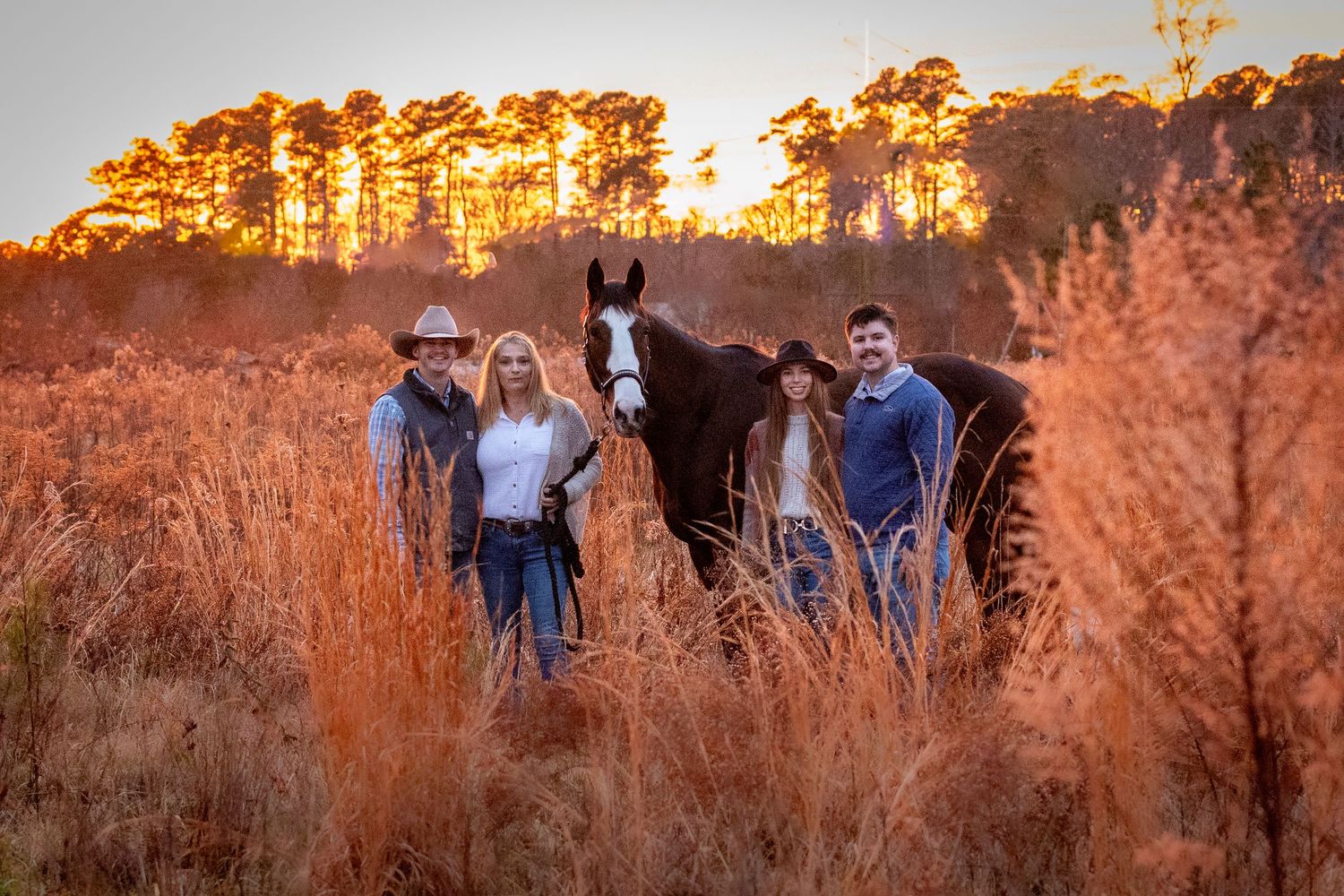Family portrait in a grassy field at sunset