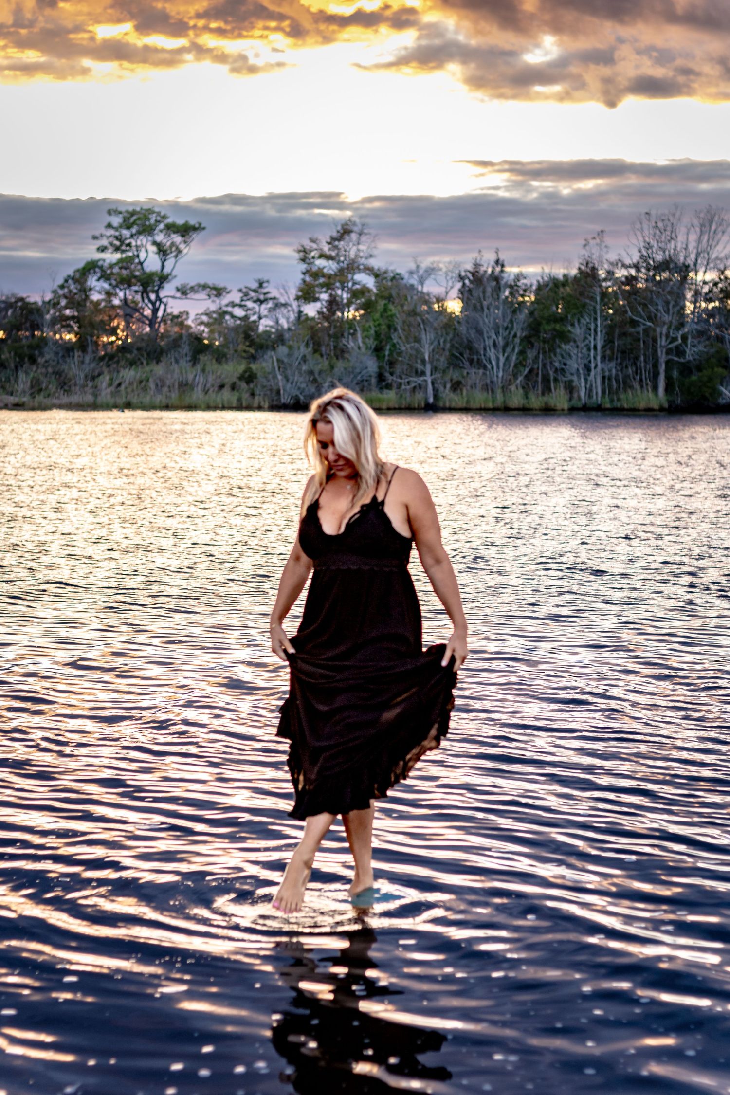 reative portrait of a woman standing in the water at sunset