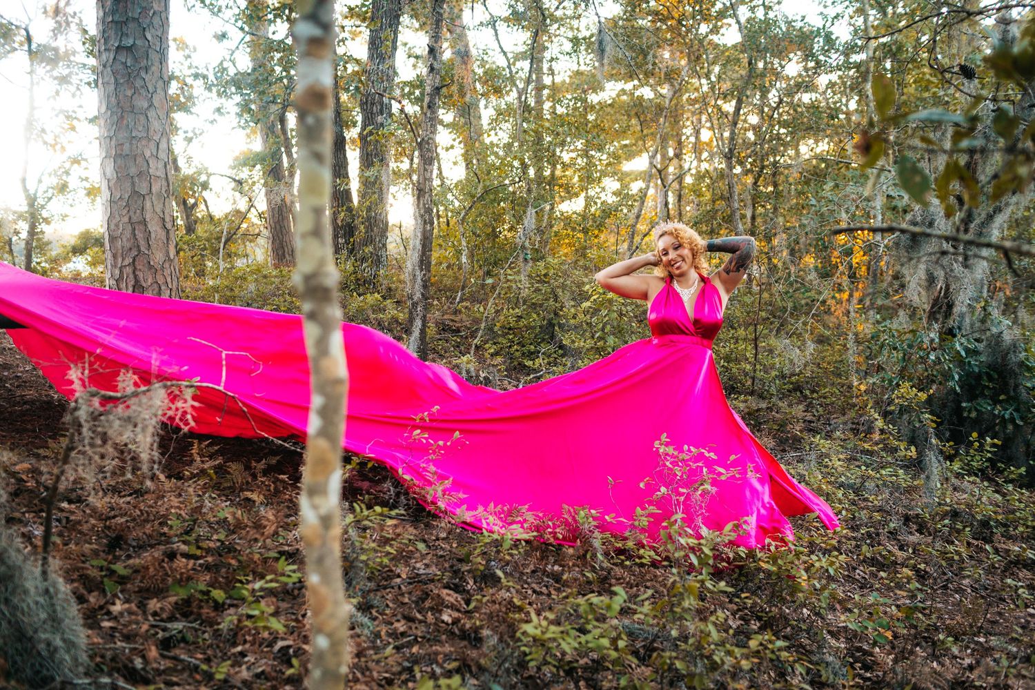 Creative portrait of a woman in a flowing pink dress in the woods