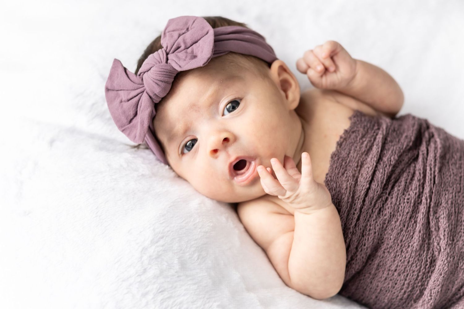 Newborn baby portrait wrapped in a purple blanket